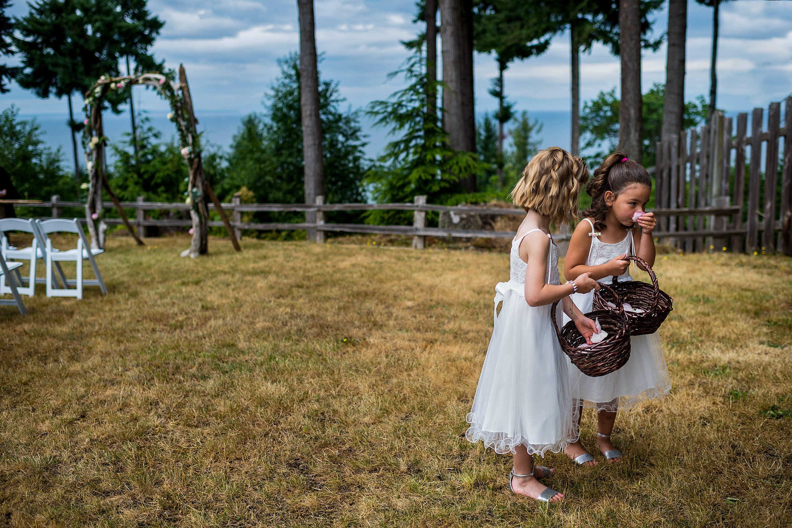 Two little girls standing on grass in front of a lake in BC - Qualicum Wedding Photographer