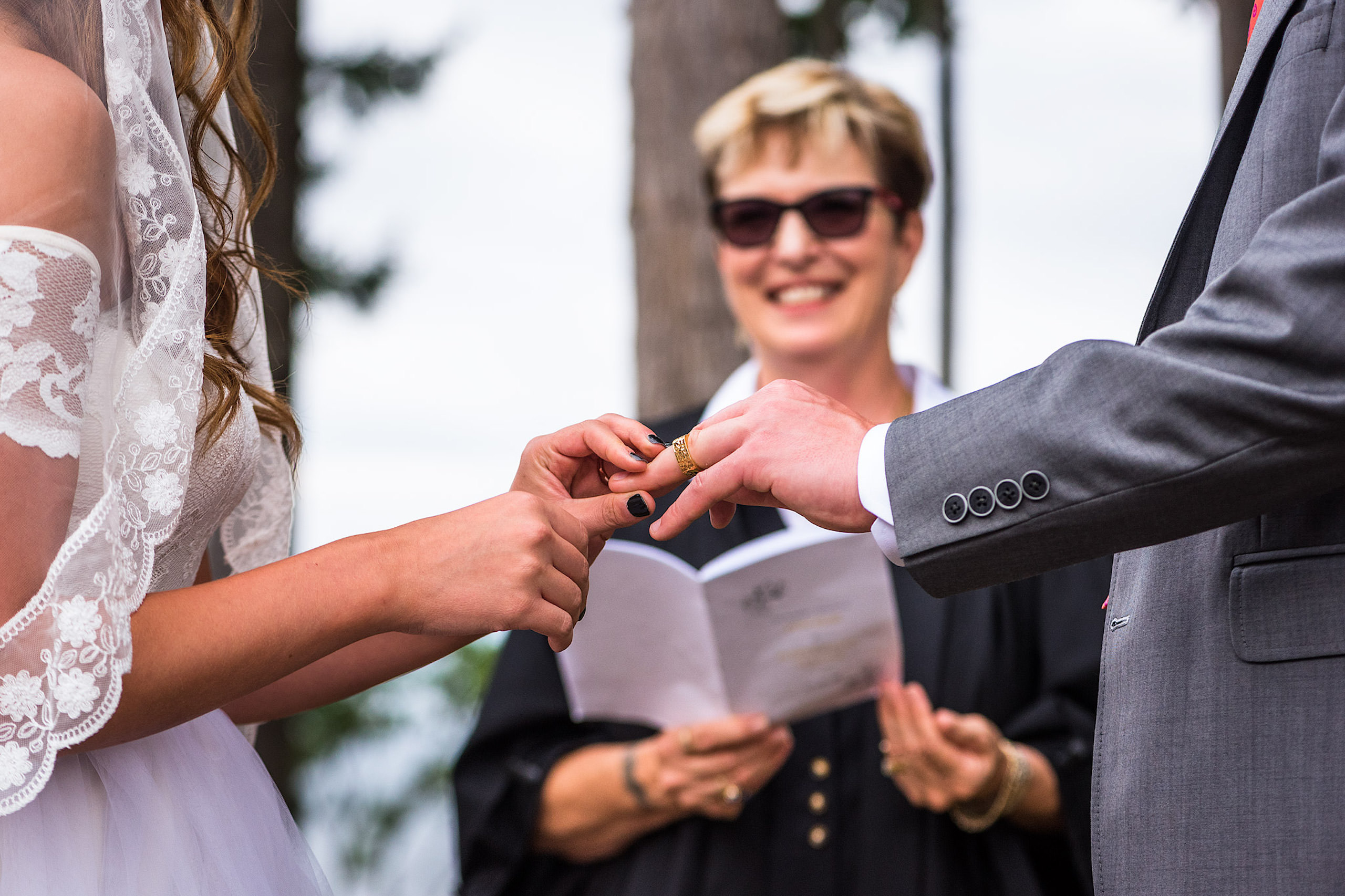 A bride putting on a ring on a grooms finger - Qualicum Wedding Photographer