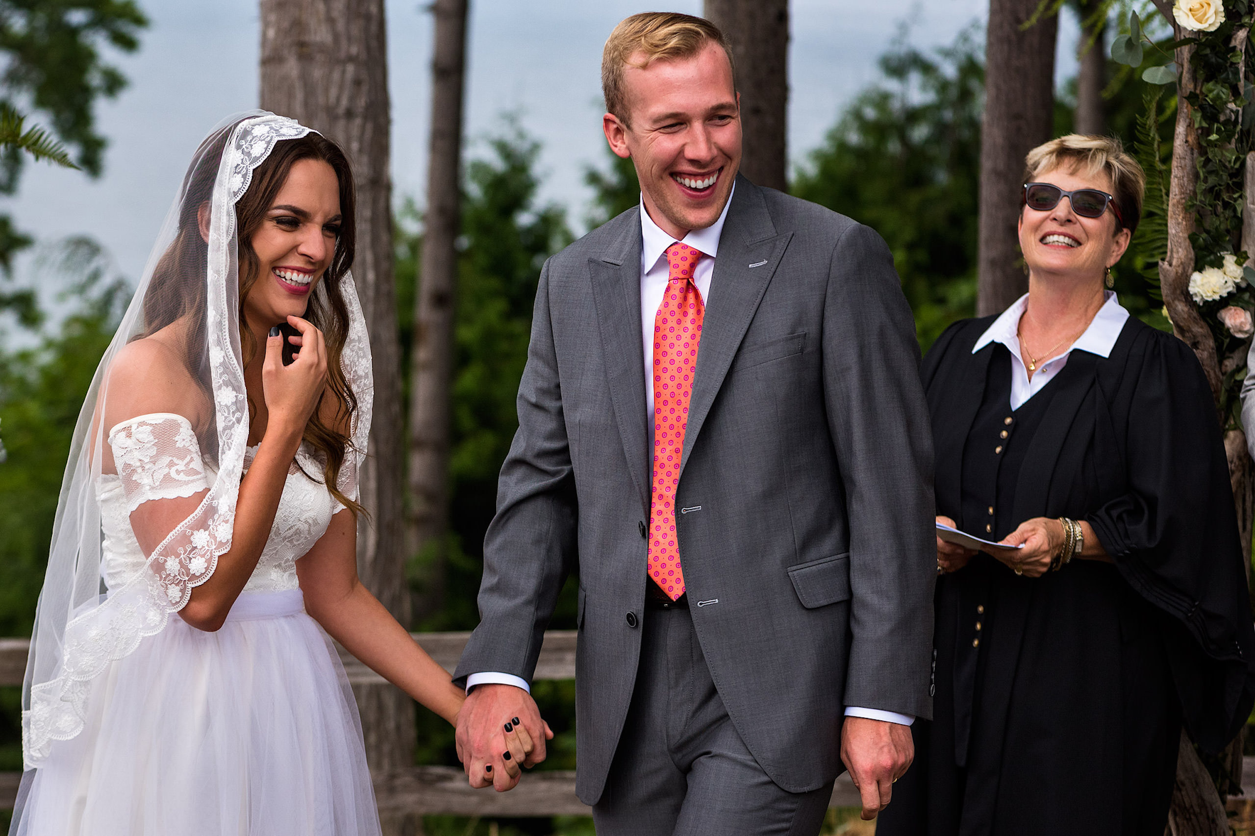 A bride and groom laughing during their ceremony in a backyard wedding - Qualicum Wedding Photographer