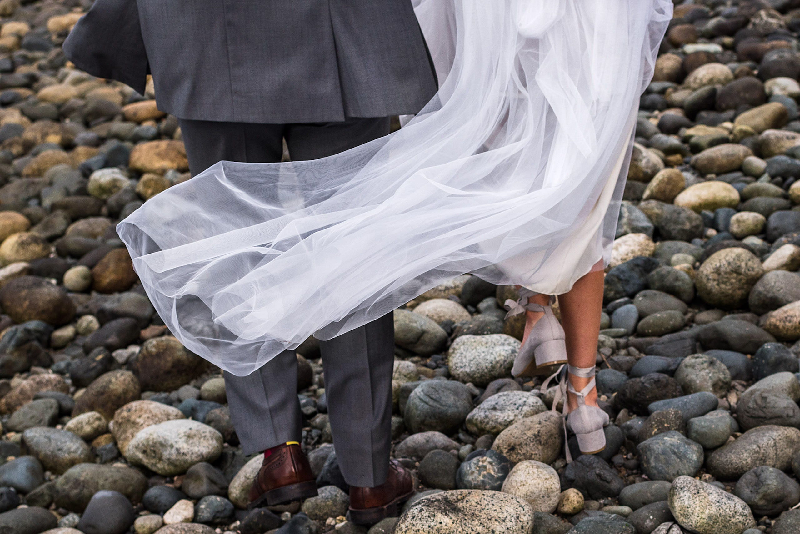 A close up of the back of a bride and groom walking on a beach in BC - Qualicum Wedding Photographer