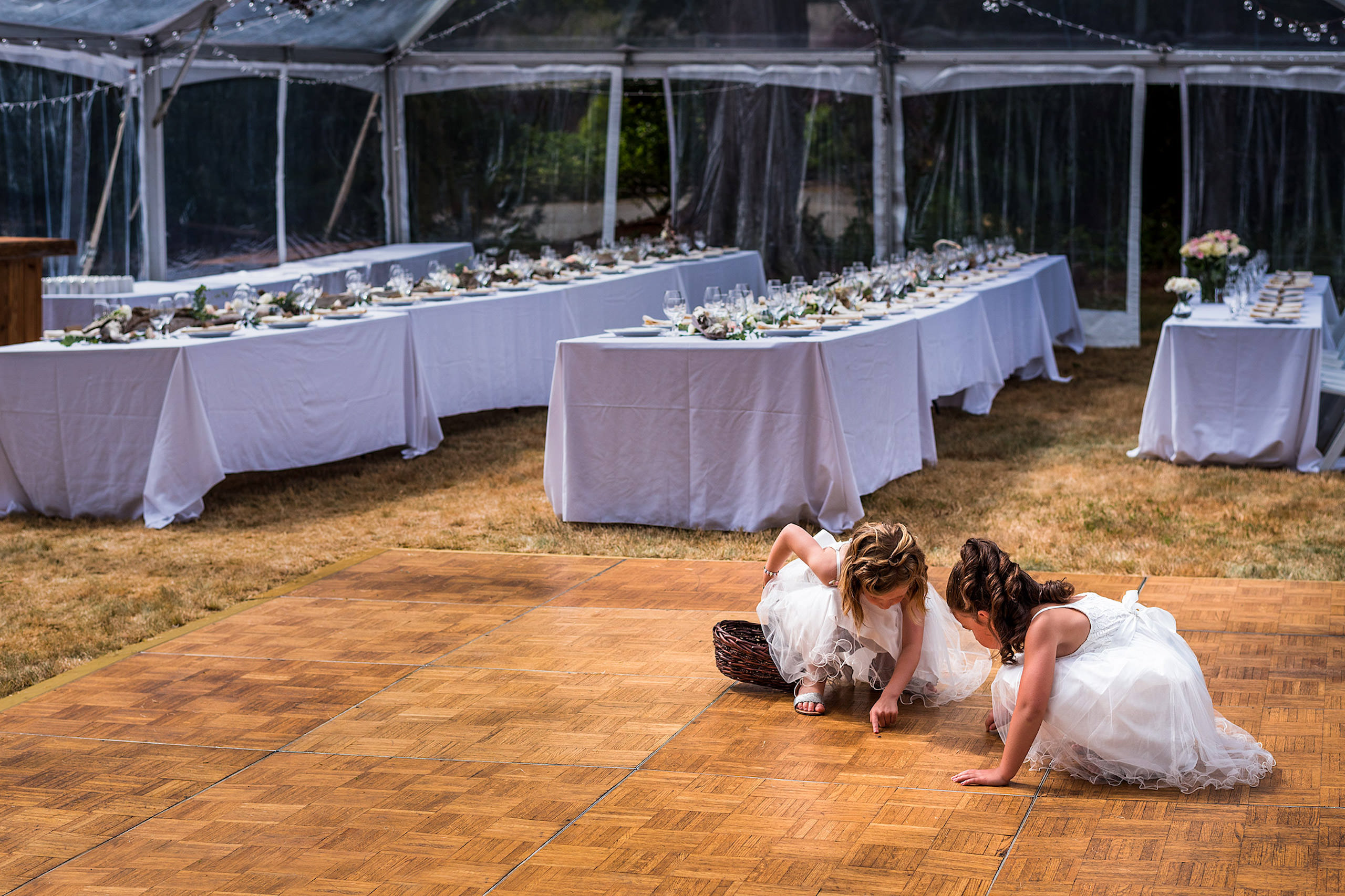 Two little flower girls looking at a bug on the dance floor - Qualicum Wedding Photographer