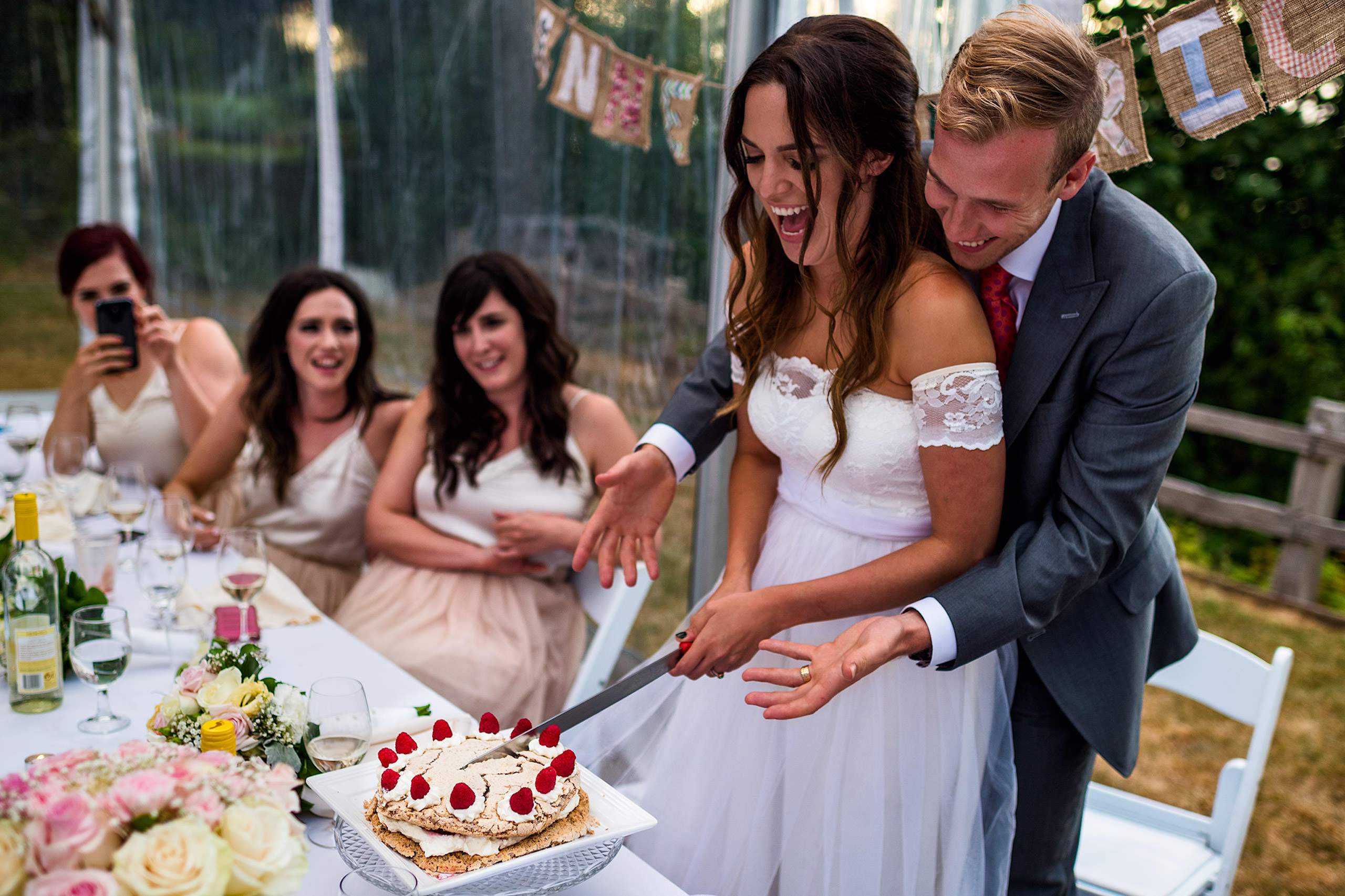 A bride and groom cutting their wedding cake in a tent - Qualicum Wedding Photographer