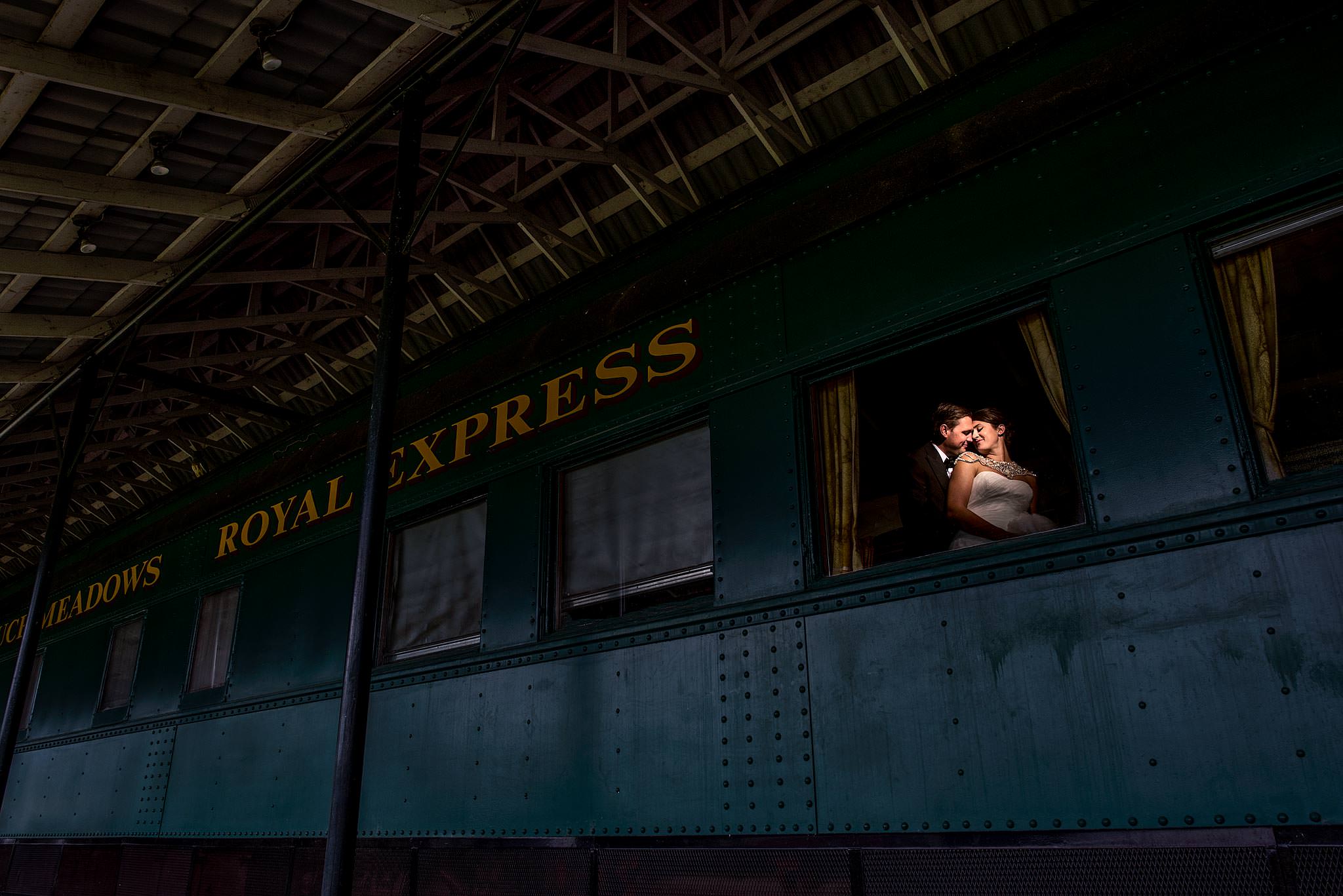 bride and groom embracing in the window of a historic train car by calgary wedding photography sean leblanc