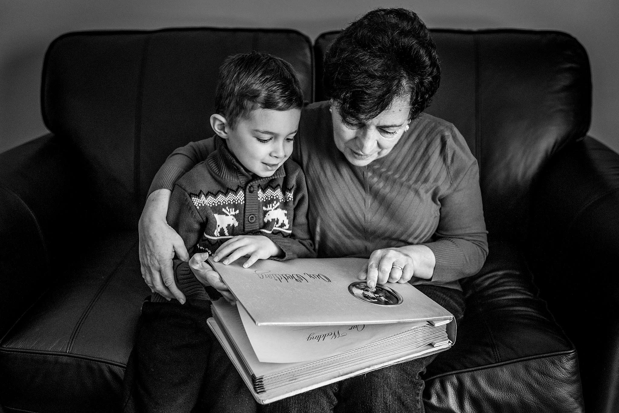 a grandma pointing to her wedding album with her grandson by top wedding photographer sean leblanc