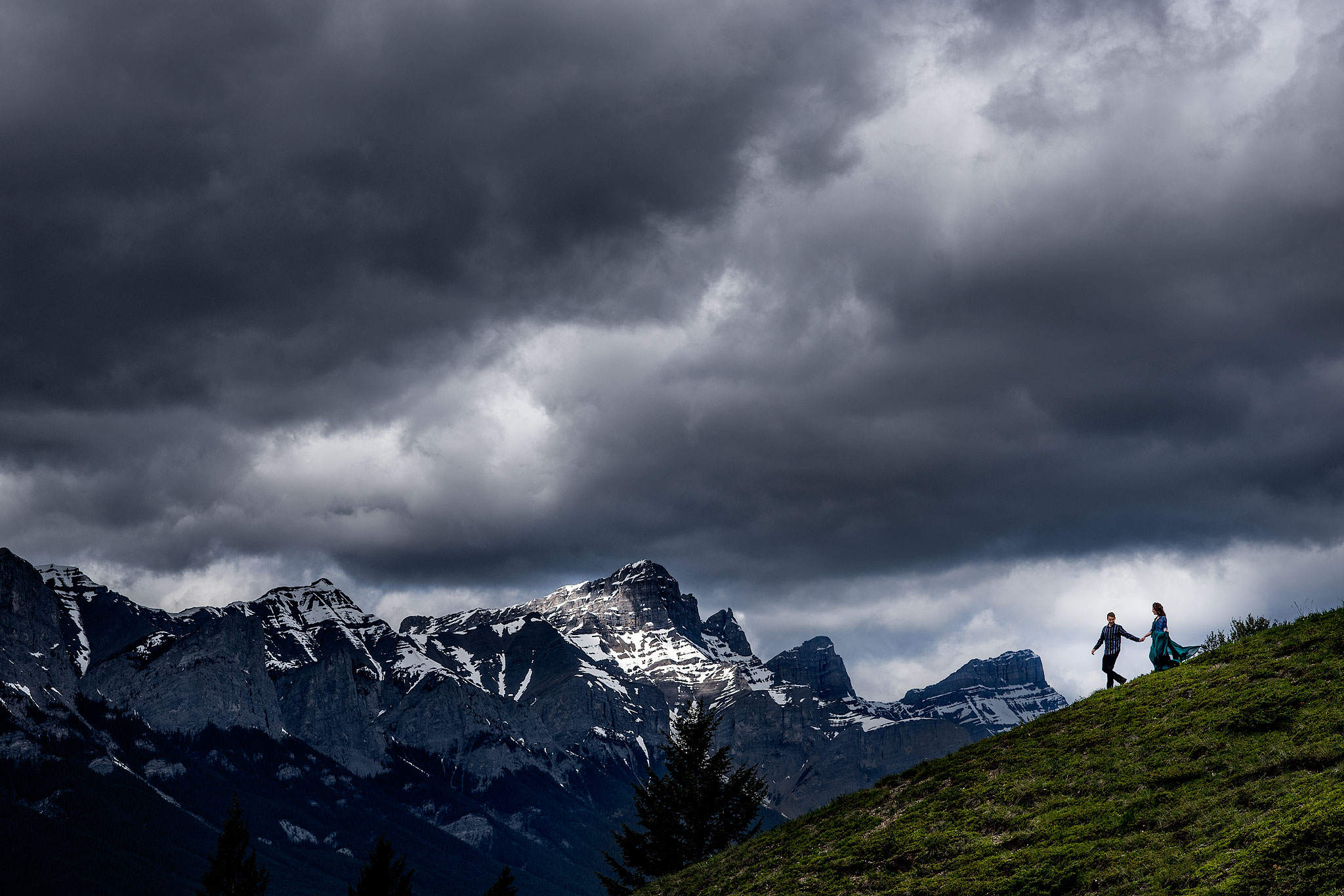 a couple walking down the side of a mountain by top calgary engagement photographer sean leblanc