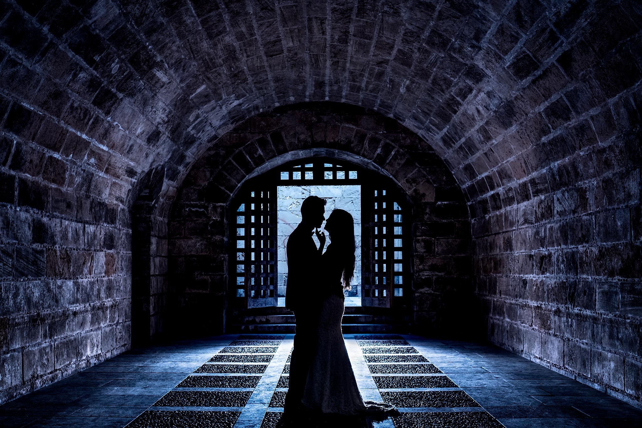 bride and groom silhouetted in a cave of a Spanish castle - Mallorca Wedding Photographer