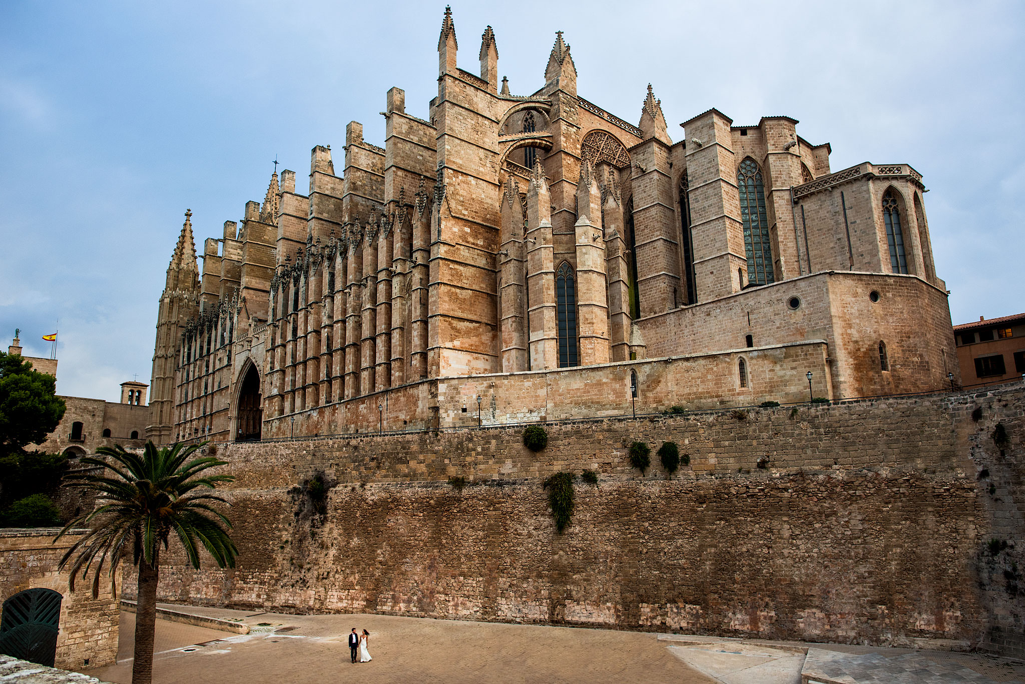 a bride and groom walking by a Spanish castle by destination wedding photographers