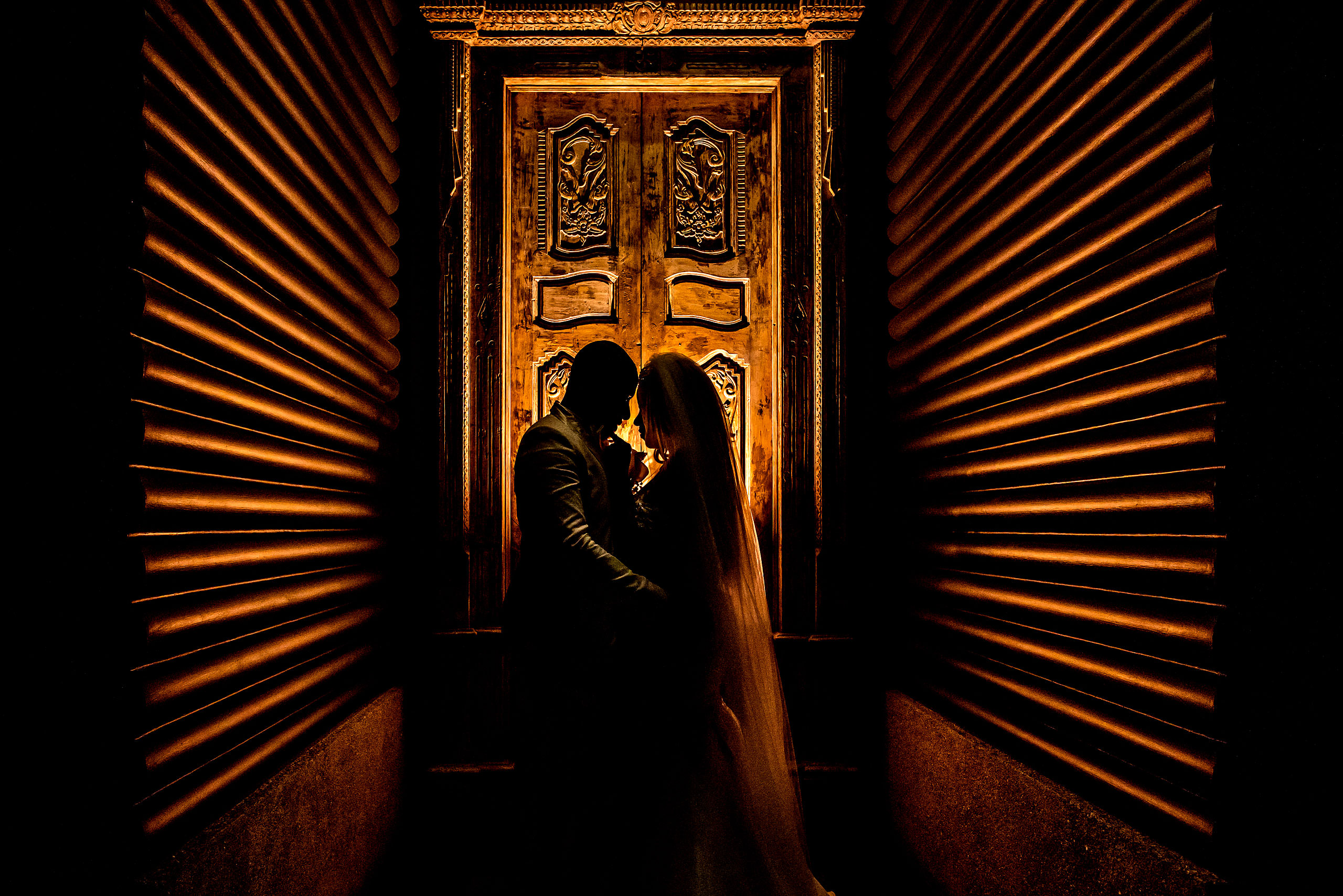 bride and groom silhouetted against a carved door at Zephyr Palace Destination Wedding in Costa Rica by Sean LeBlanc