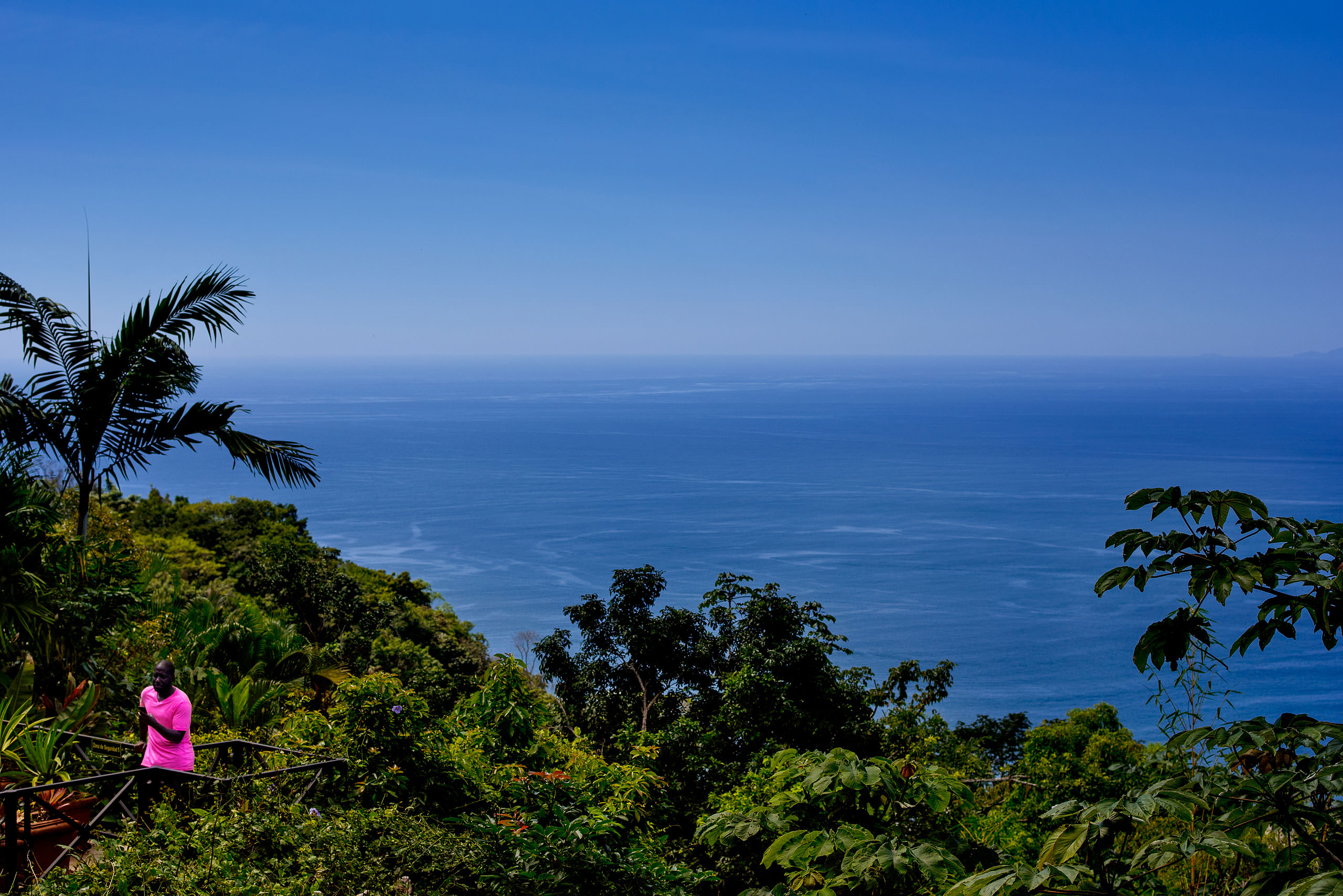 man wearing a pink shirt near the ocean at Zephyr Palace Destination Wedding in Costa Rica by Sean LeBlanc