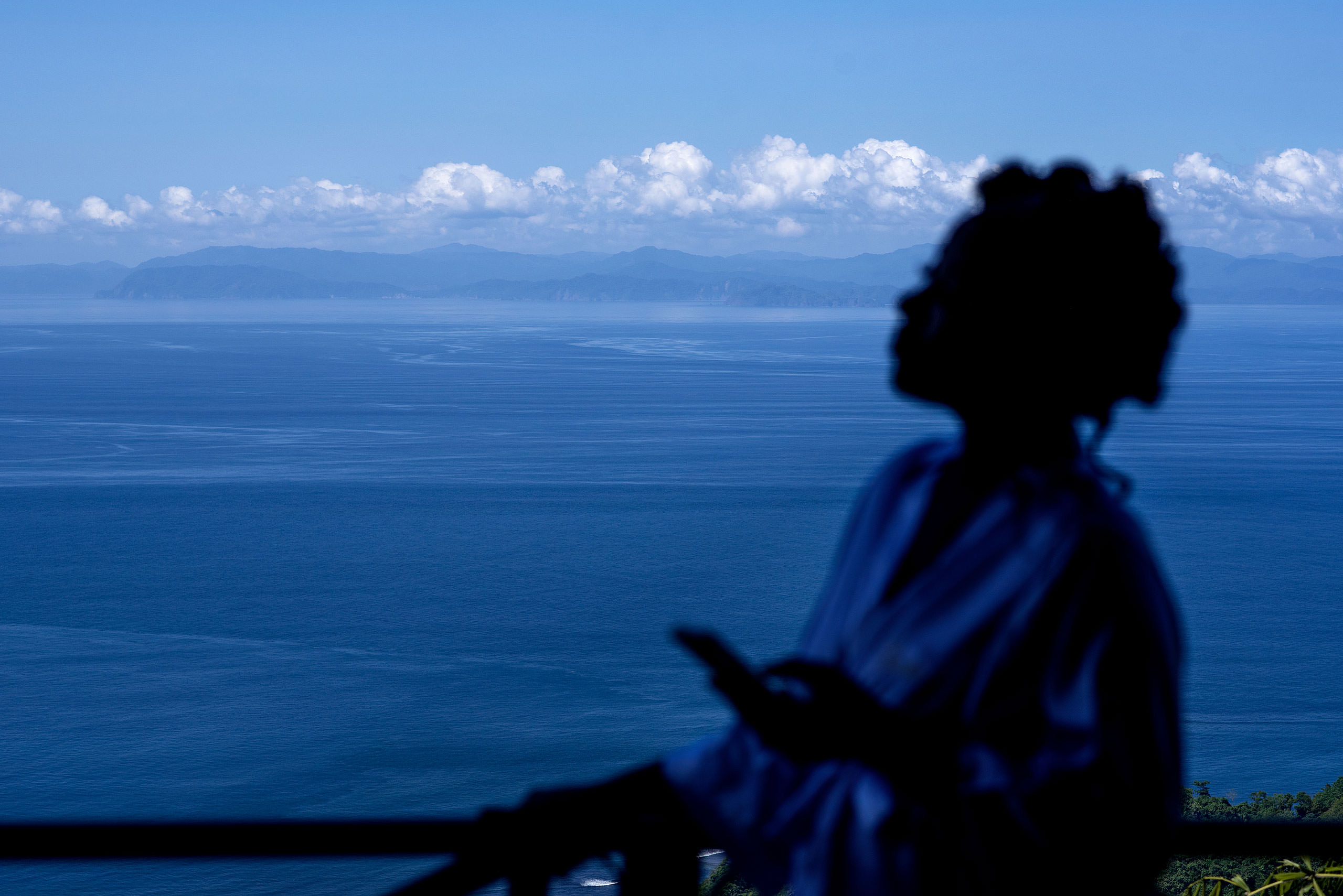 a women standing on a balcony overlooking the ocean at Zephyr Palace Destination Wedding in Costa Rica by Sean LeBlanc