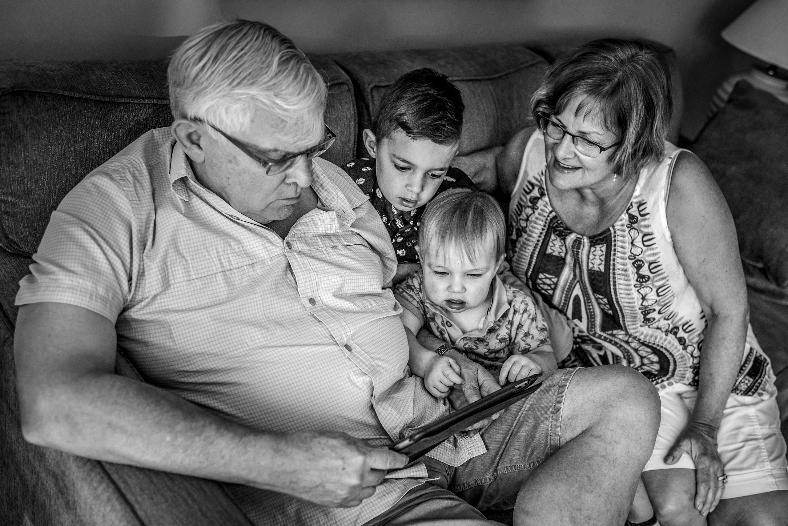 grandma and grandpa with their grandsons looking at an iPad by destination family photographers sean leblanc