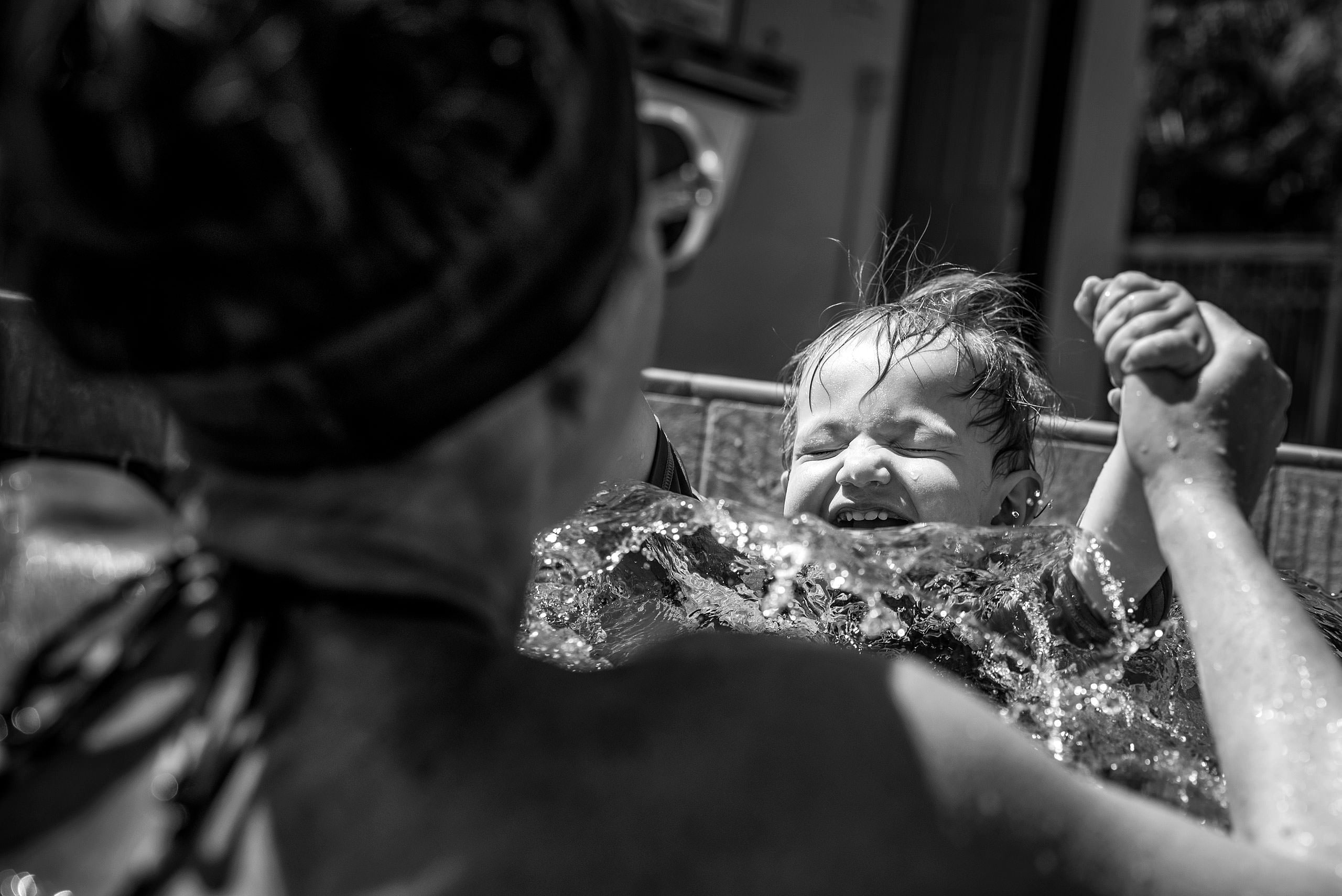 a young boy and his mom splashing in a pool by destination family photographers sean leblanc