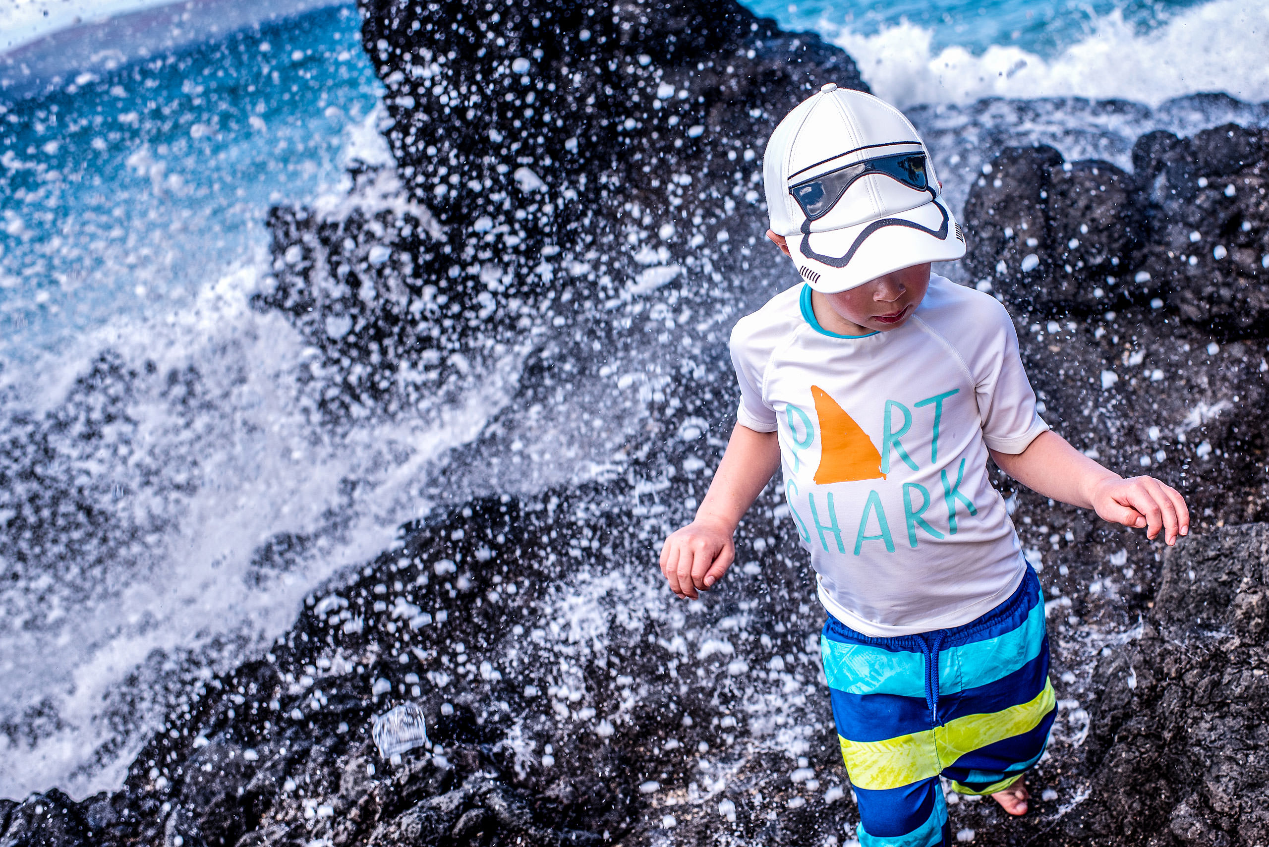 a young boy being splashed by water by destination family photographers sean leblanc