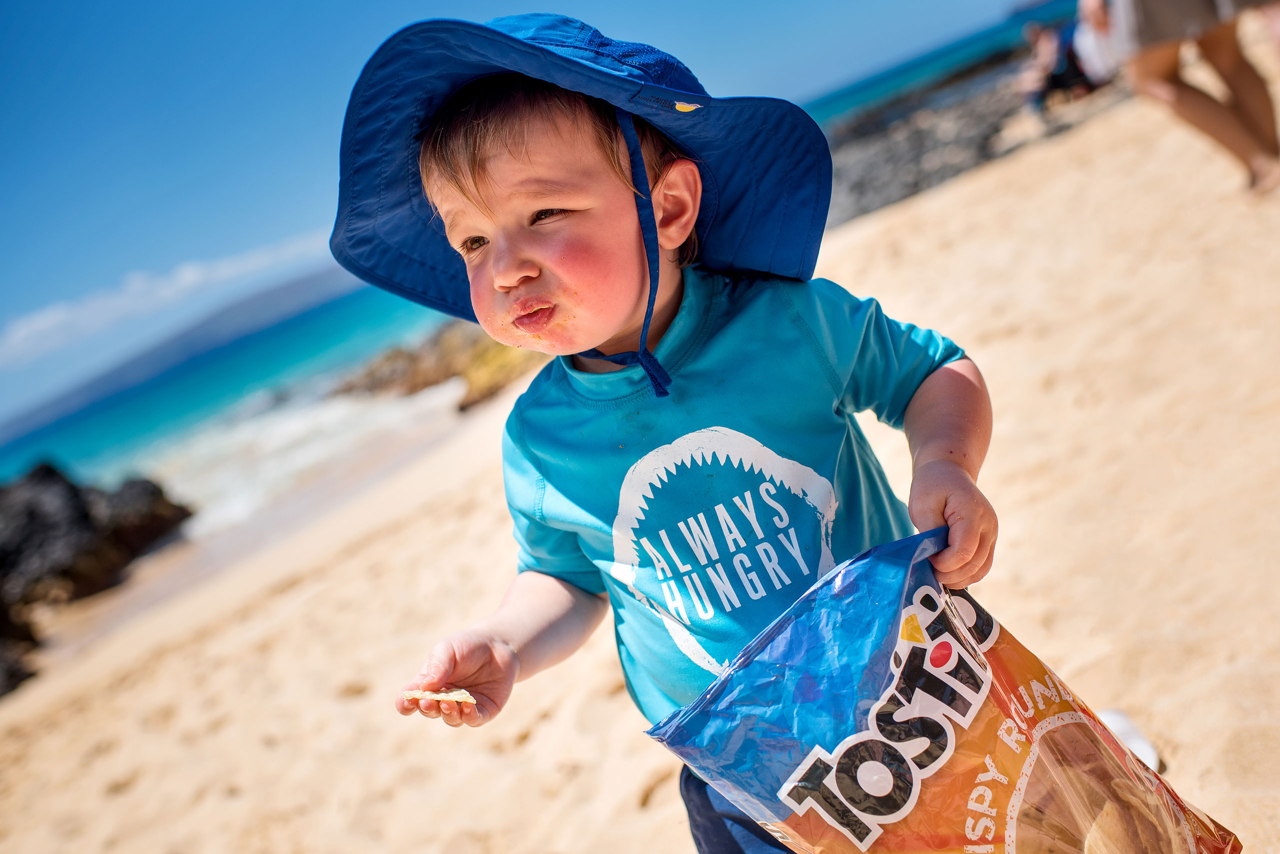 a young boy eating doritos on the beach by destination family photographers sean leblanc