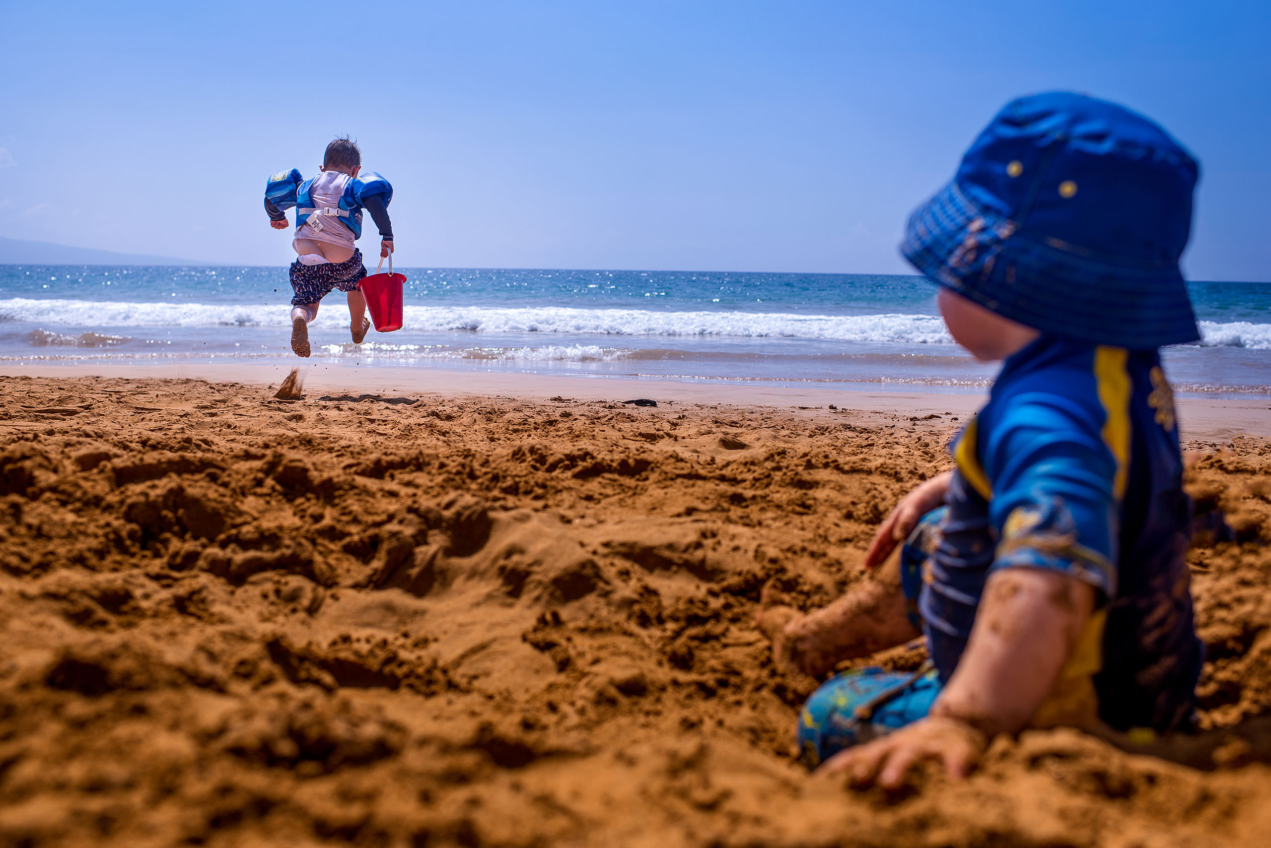 a boy running on a beach towards the ocean by destination family photographers sean leblanc