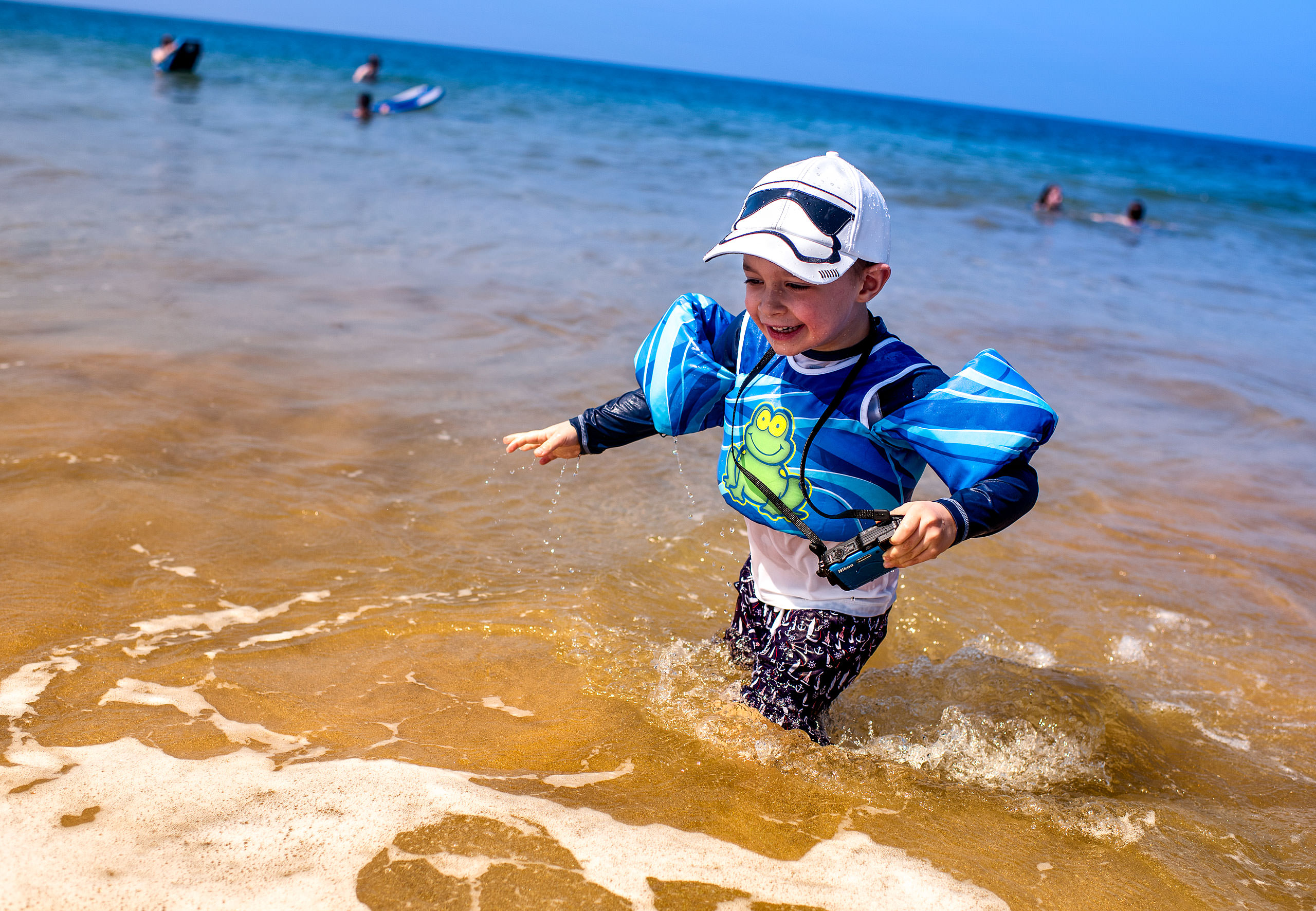 a young boy playing in the ocean by destination family photographers sean leblanc