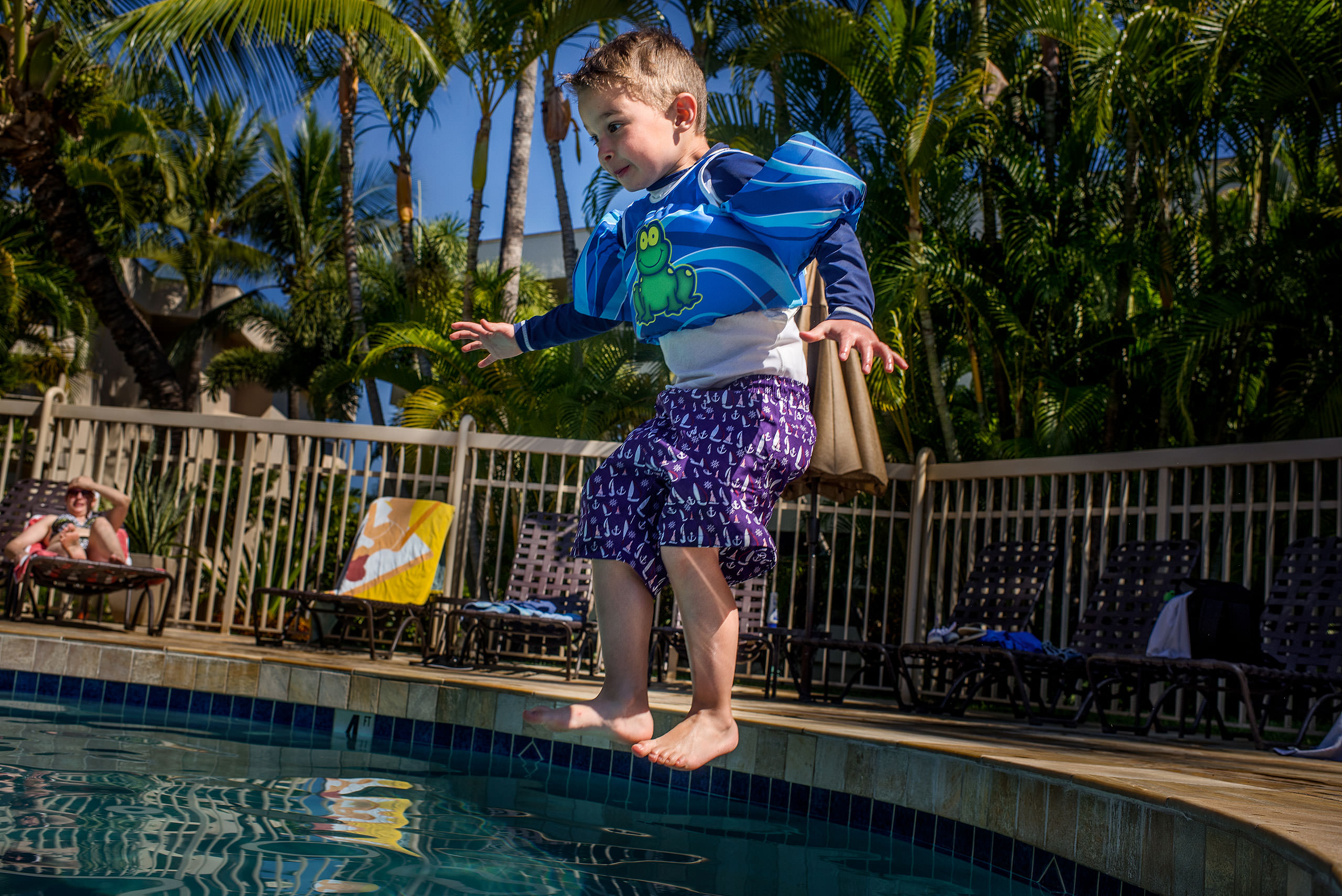 a young boy jumping into a pool by destination family photographers sean leblanc