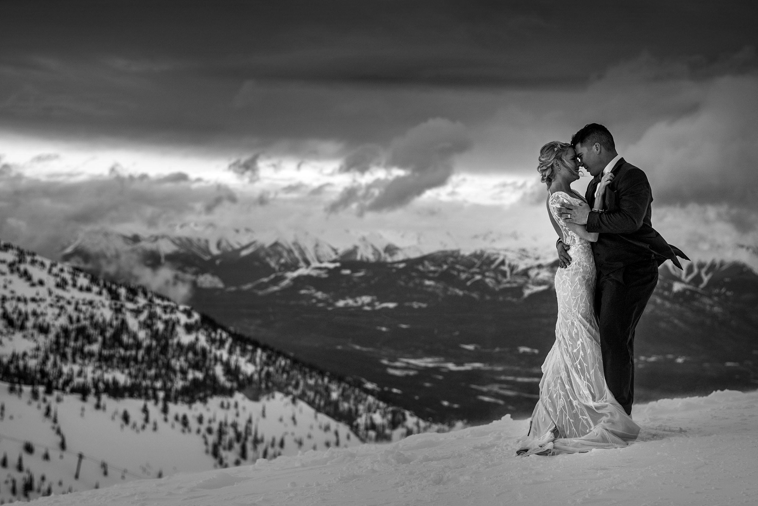 bride and groom embracing at the top of a mountain at winter kicking horse wedding