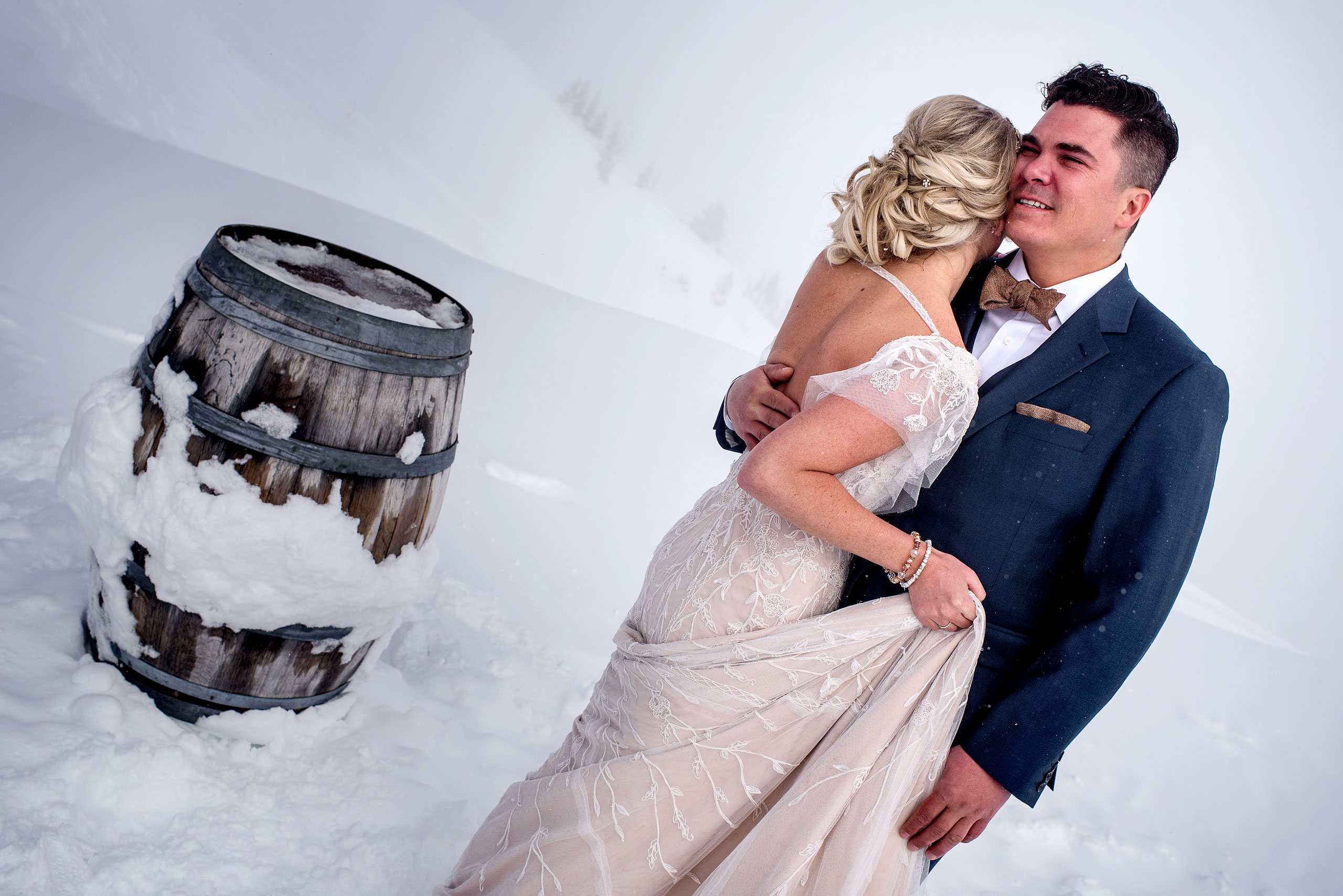 a bride and groom hugging each other at a winter kicking horse wedding by sean leblanc