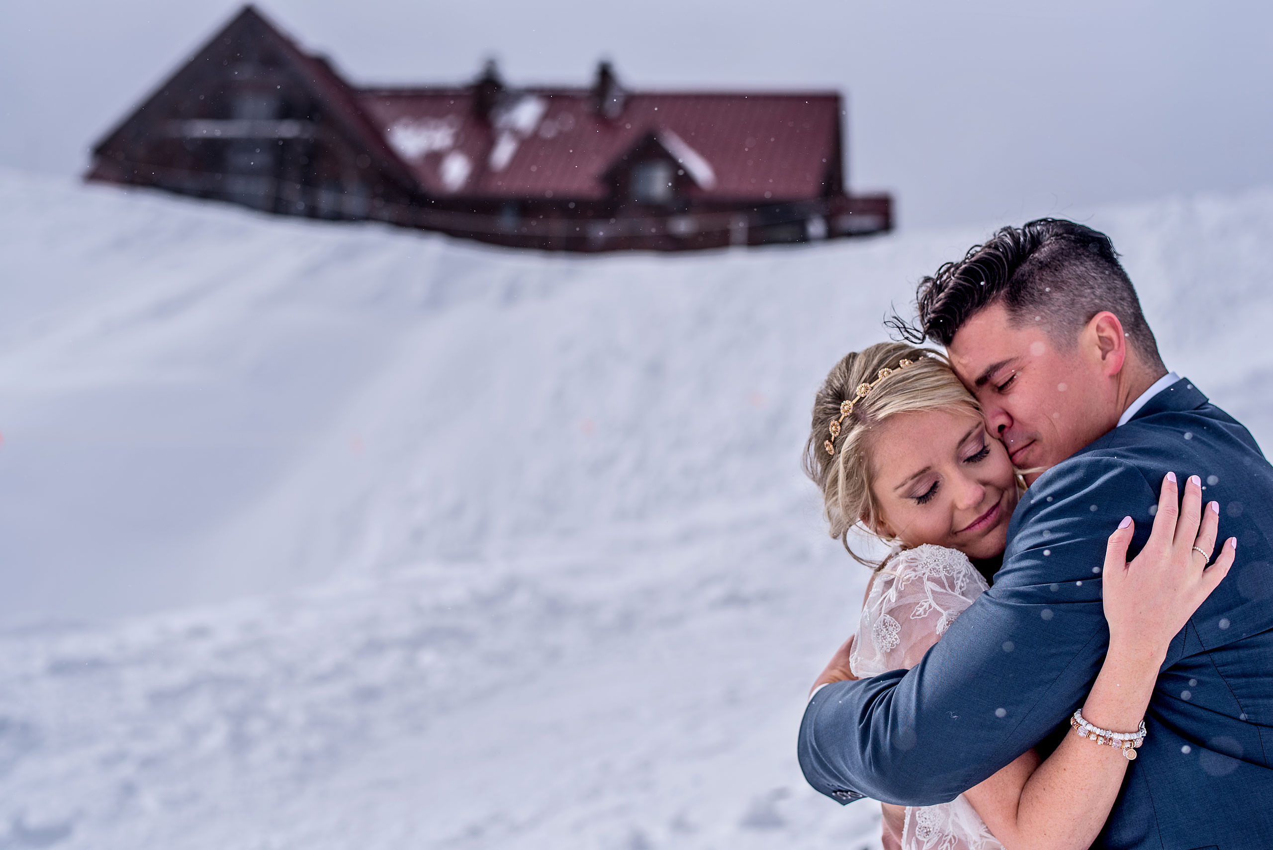 a bride and groom hugging in front of a lodge at a winter kicking horse wedding by sean leblanc