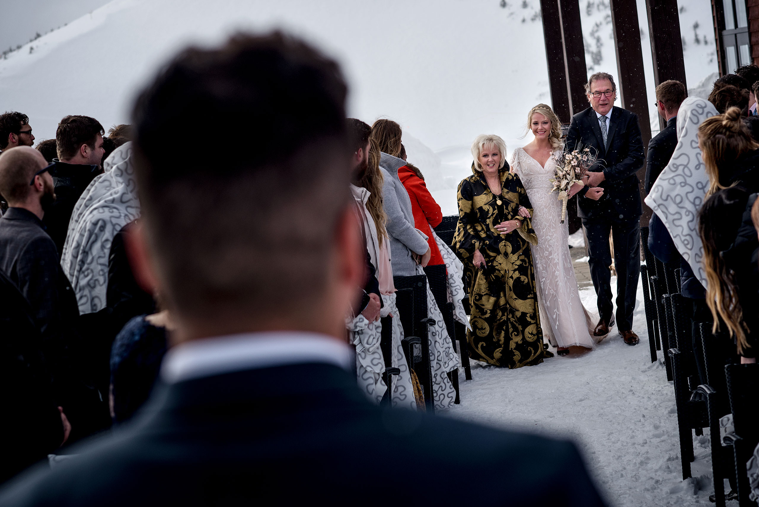 bride walking down aisle with parents at winter kicking horse wedding