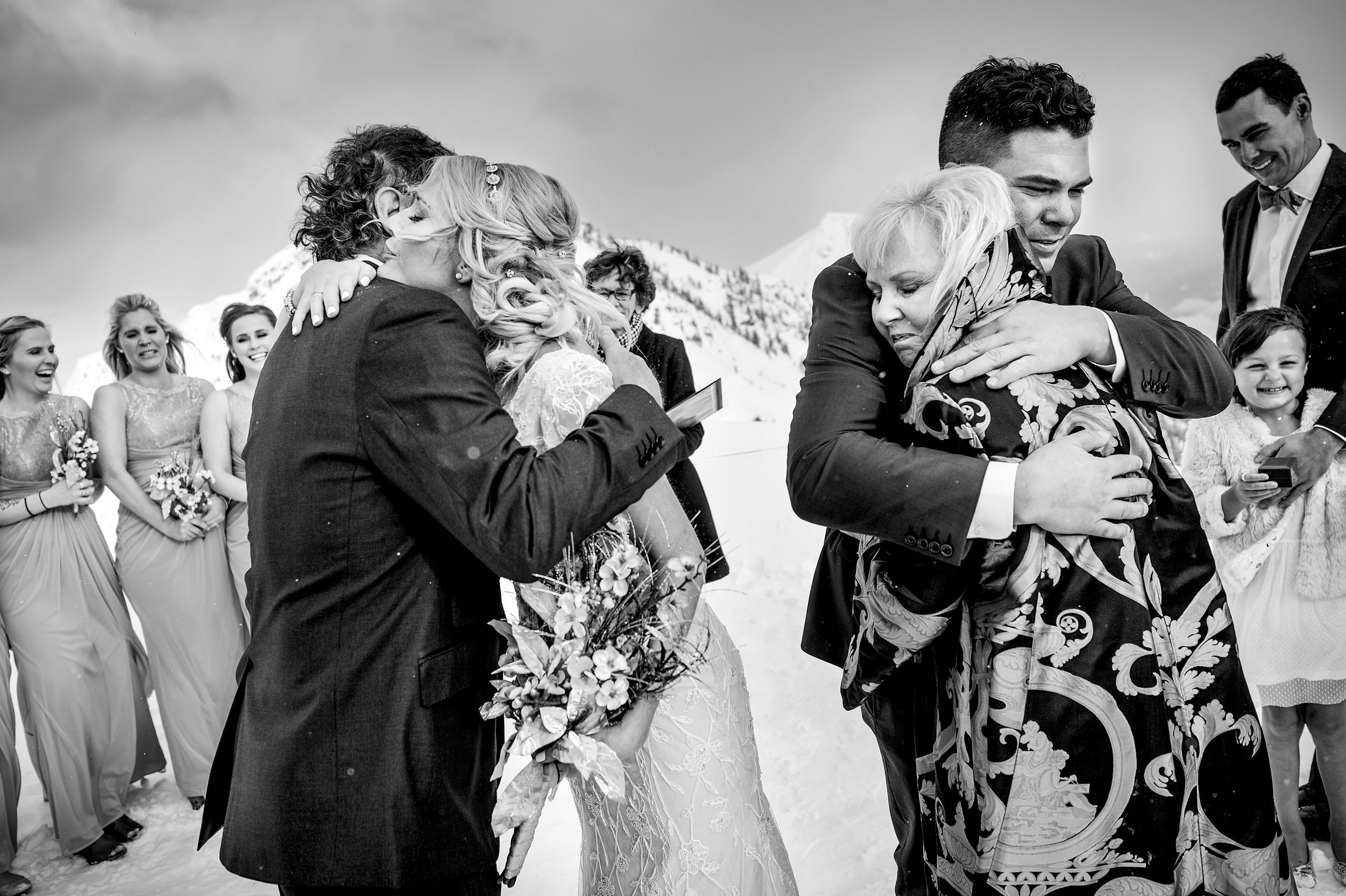 a bride and groom hugging their parents at a ceremony at a winter kicking horse wedding by sean leblanc