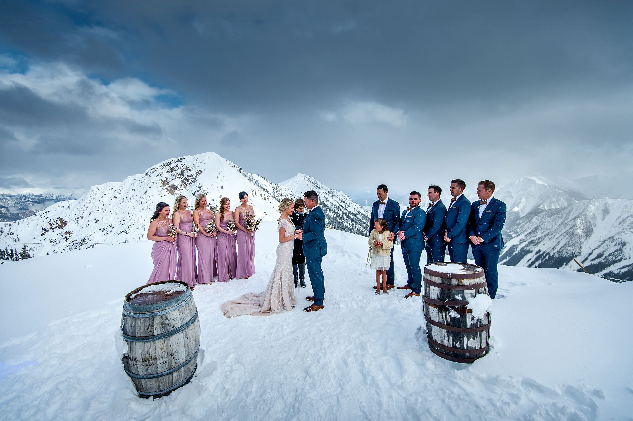 a bridal party standing at the top of a mountain at a winter kicking horse wedding by sean leblanc