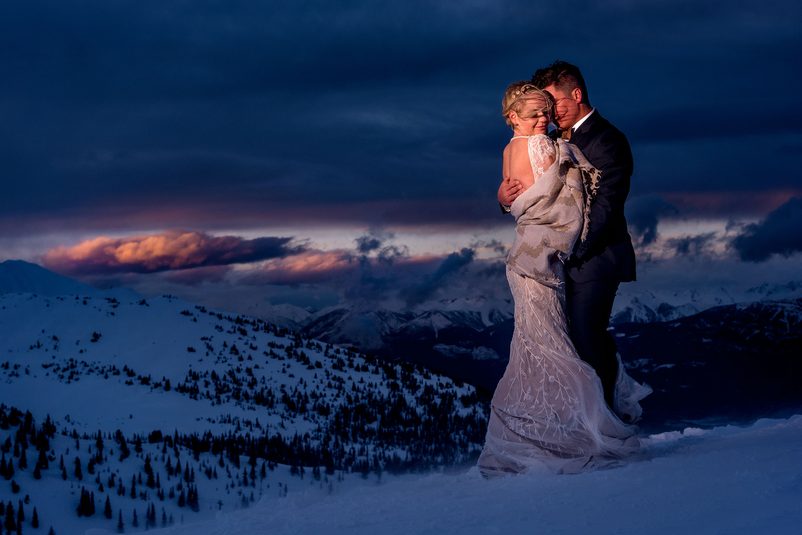 bride and groom on the top of a mountain in the winter at dusk at winter kicking horse wedding