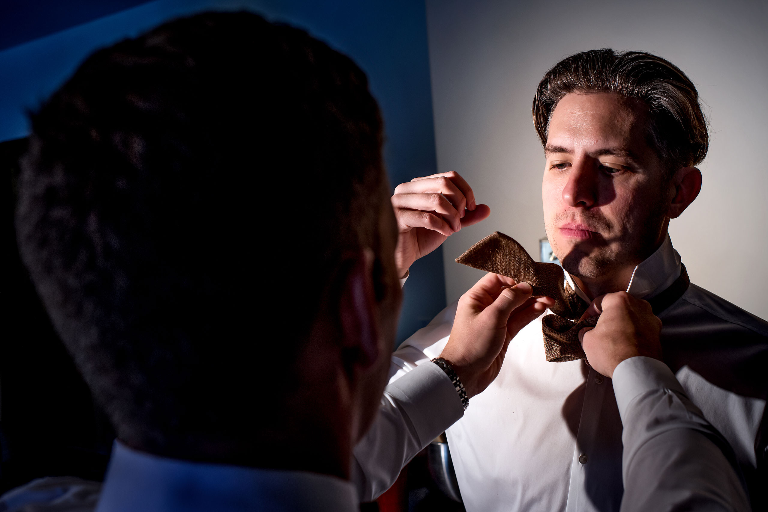 groomsmen helping each other tie ties before a wedding day - winter kicking horse wedding