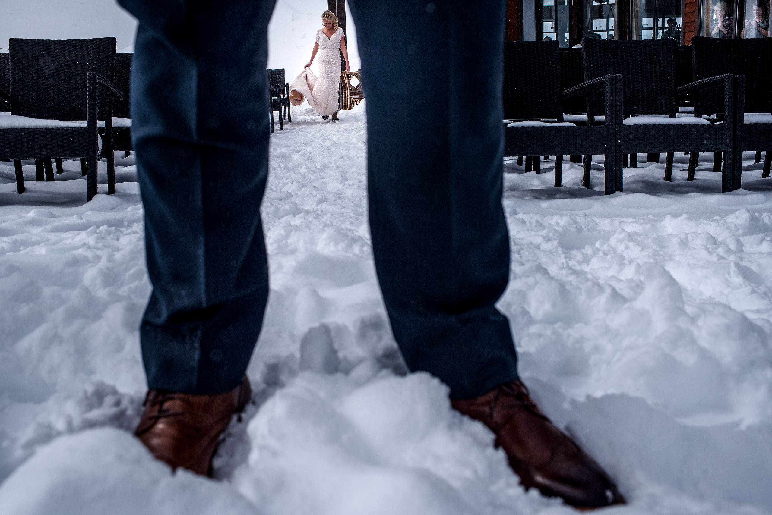 a bride framed by grooms legs at a winter kicking horse wedding by sean leblanc