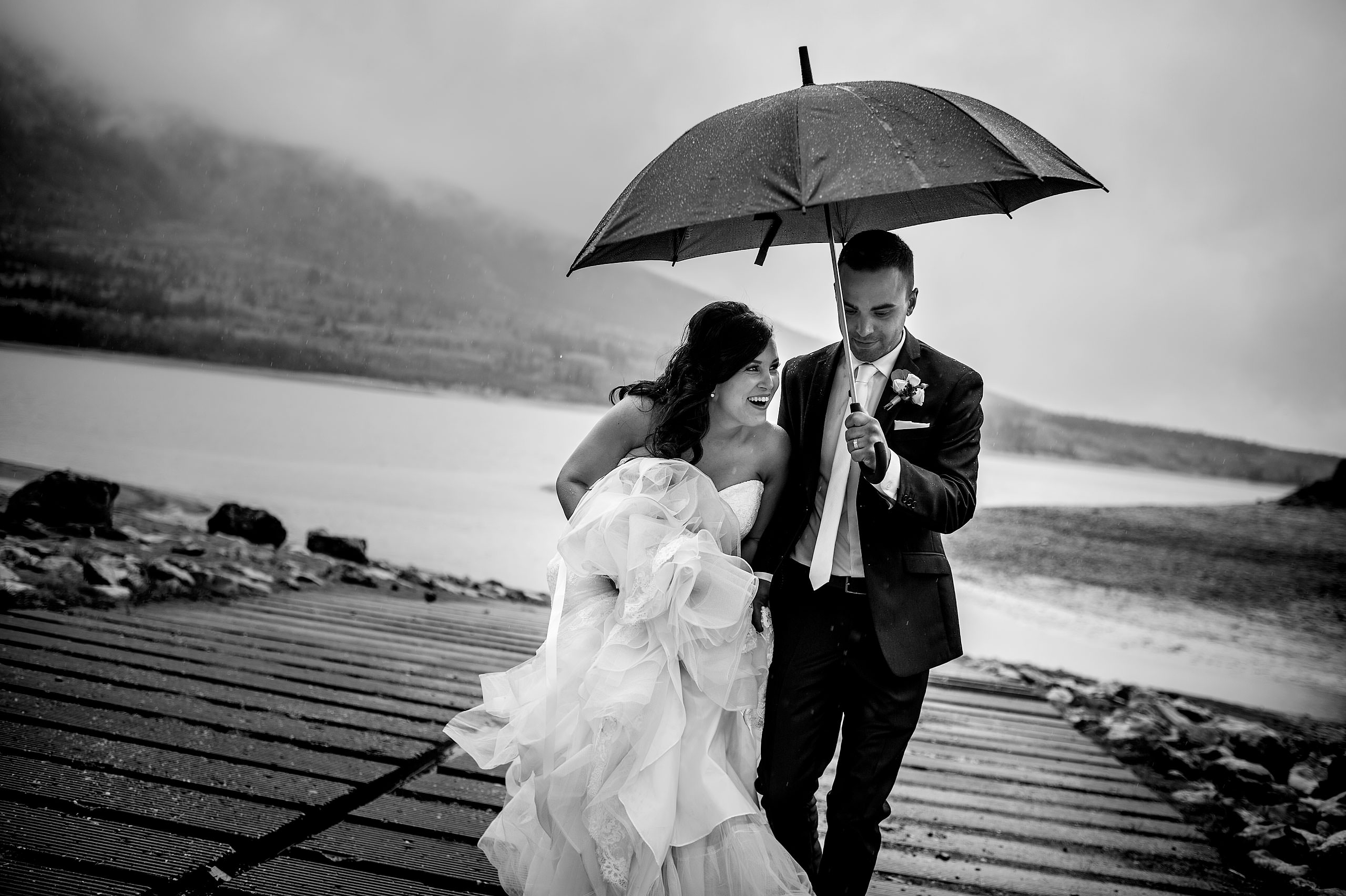 a bride and groom walking up a ramp during a rainstorm by calgary wedding photographers