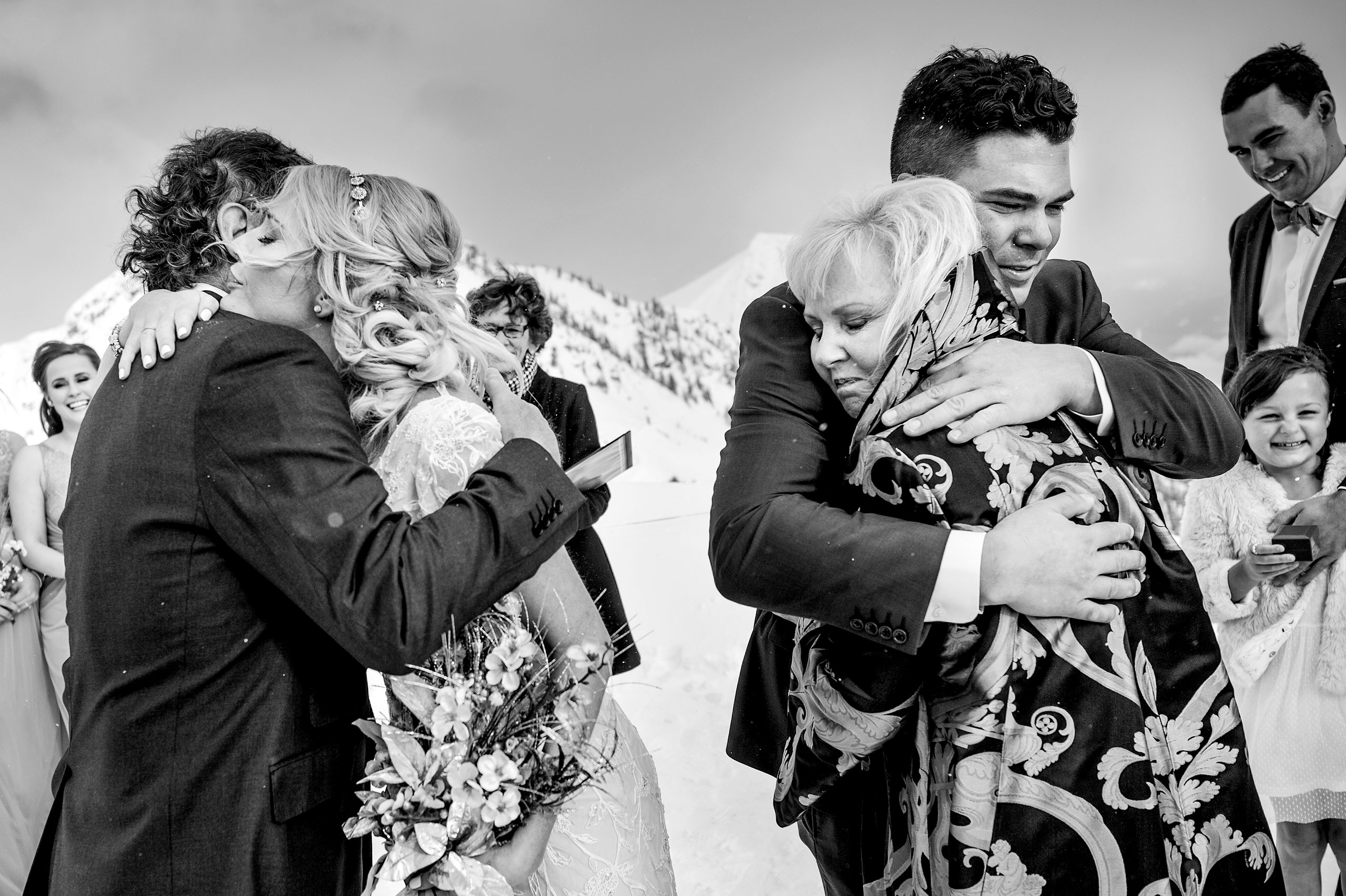 a groom hugging his mom and a bride hugging her dad at winter kicking horse wedding