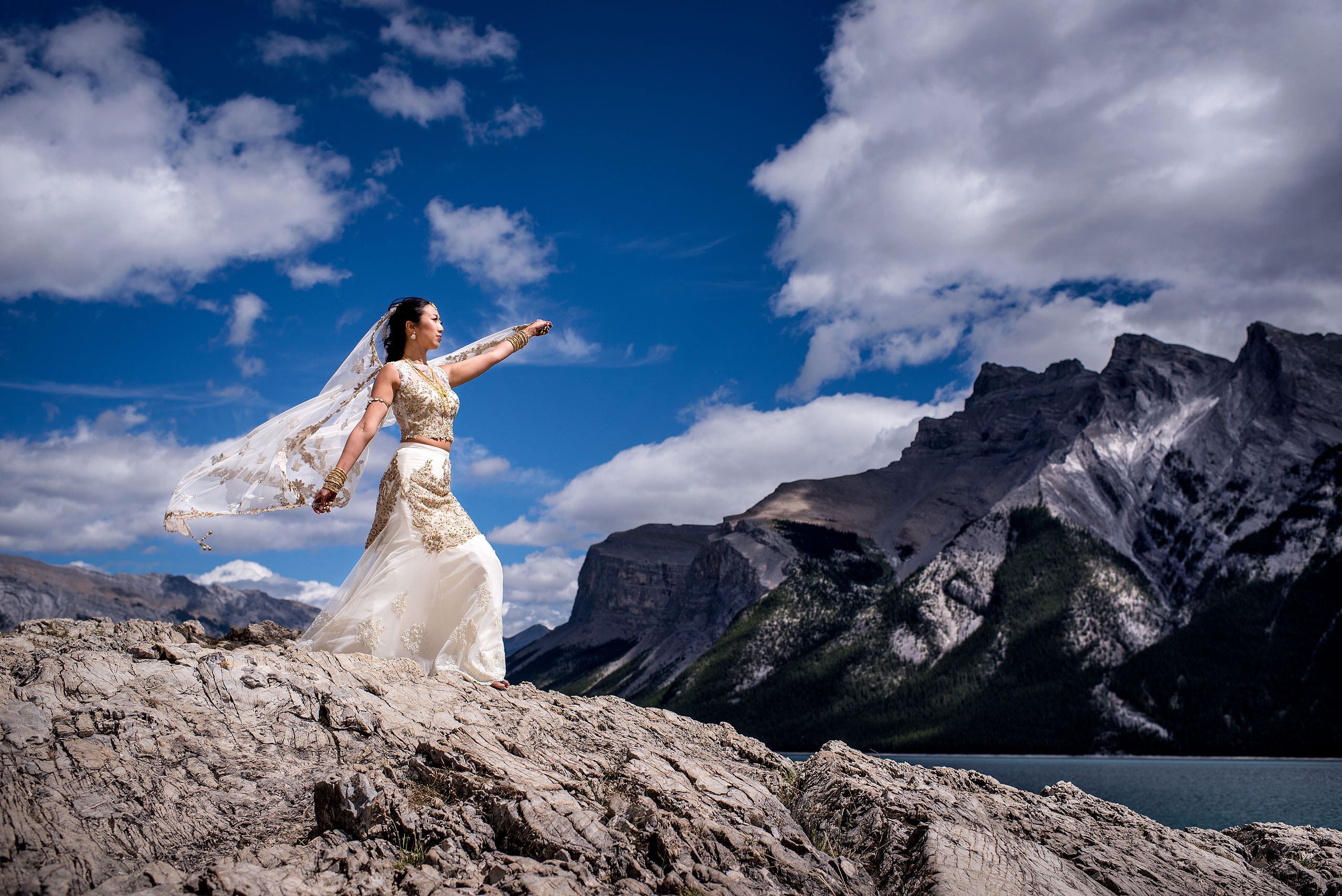 bride lifting dress while standing on a rock for cascade ballroom banff springs wedding by sean leblanc
