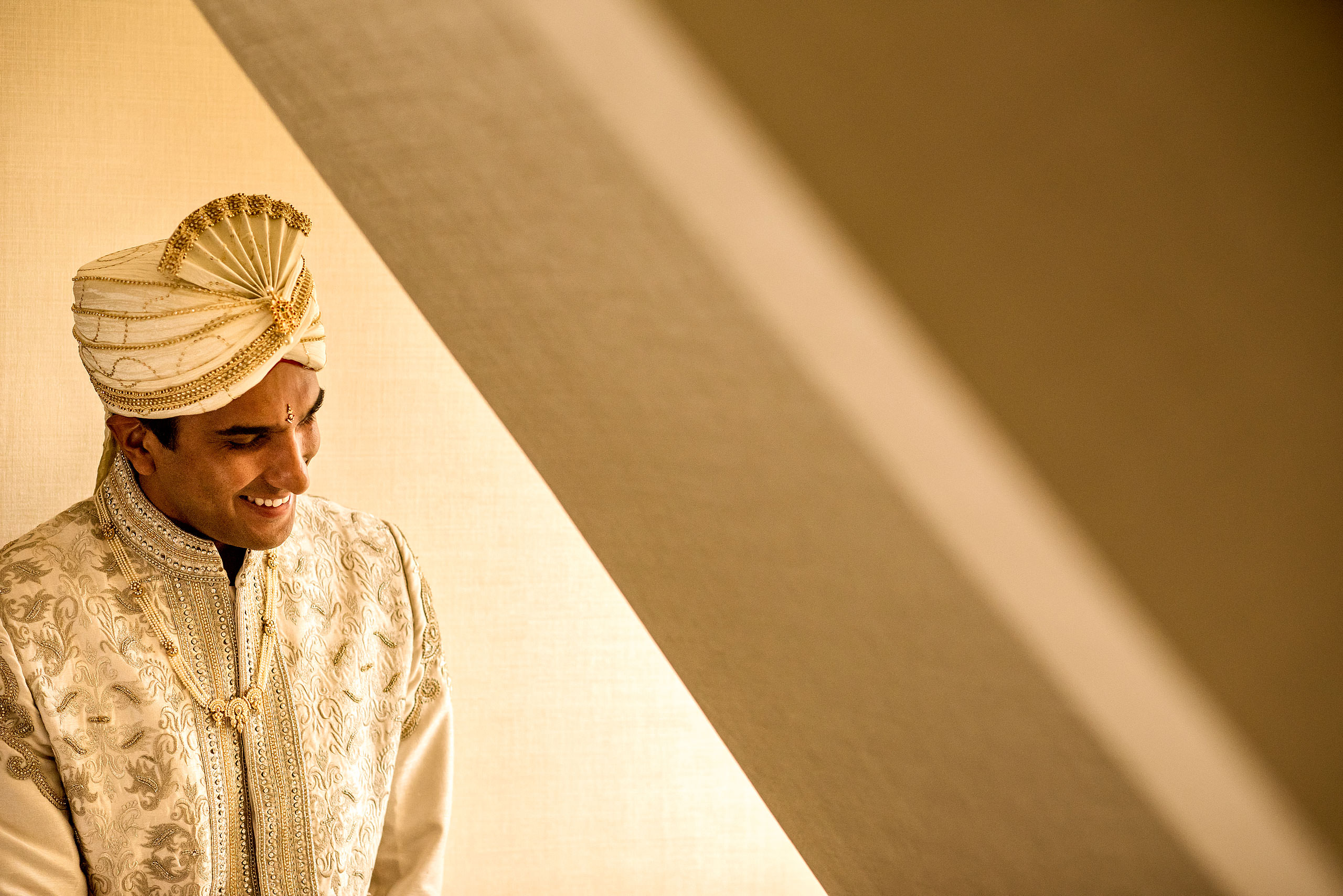 indian groom laughing by a winder for cascade ballroom banff springs wedding by sean leblanc