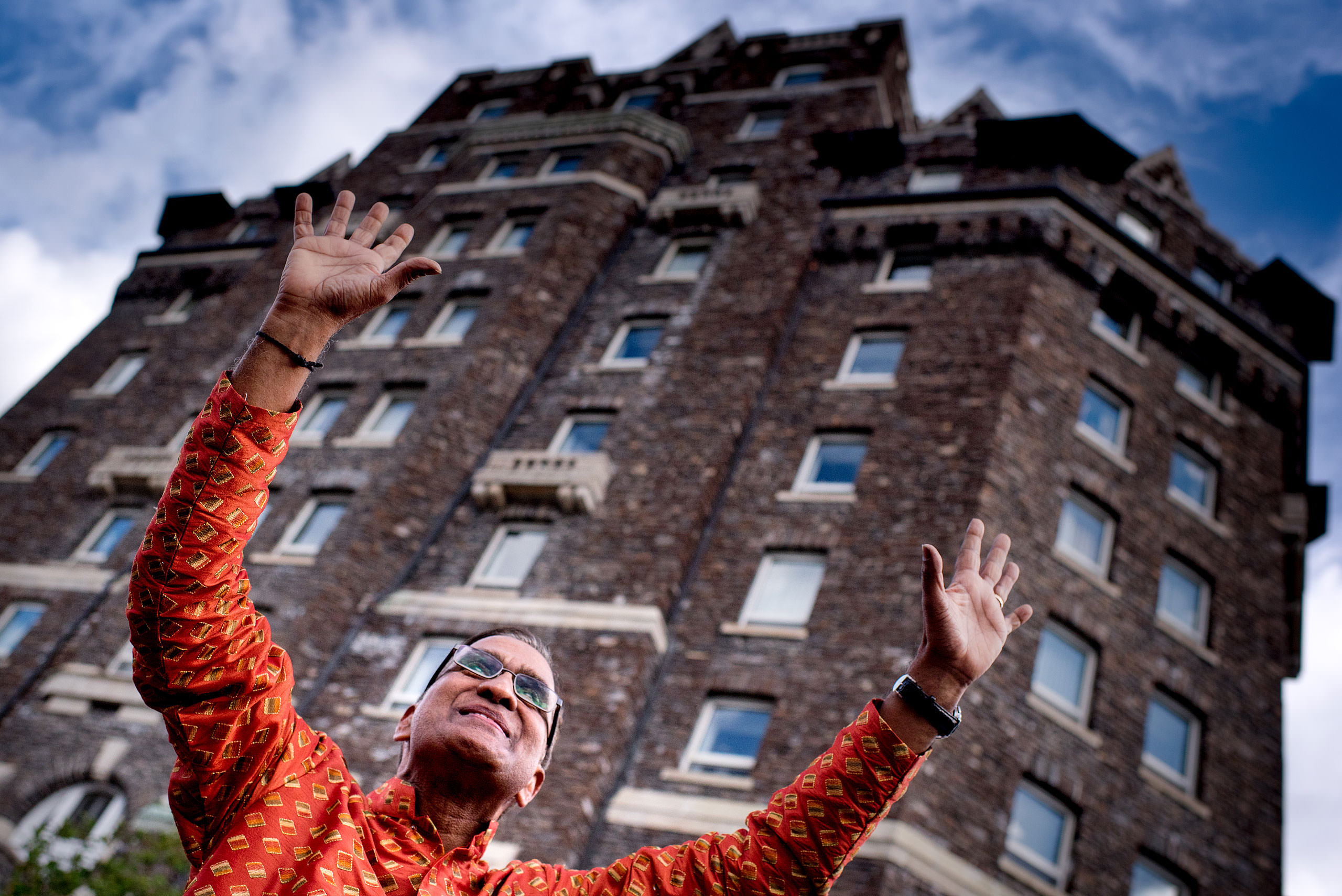 an indian man with arms in the air and hotel in the background for cascade ballroom banff springs wedding by sean leblanc