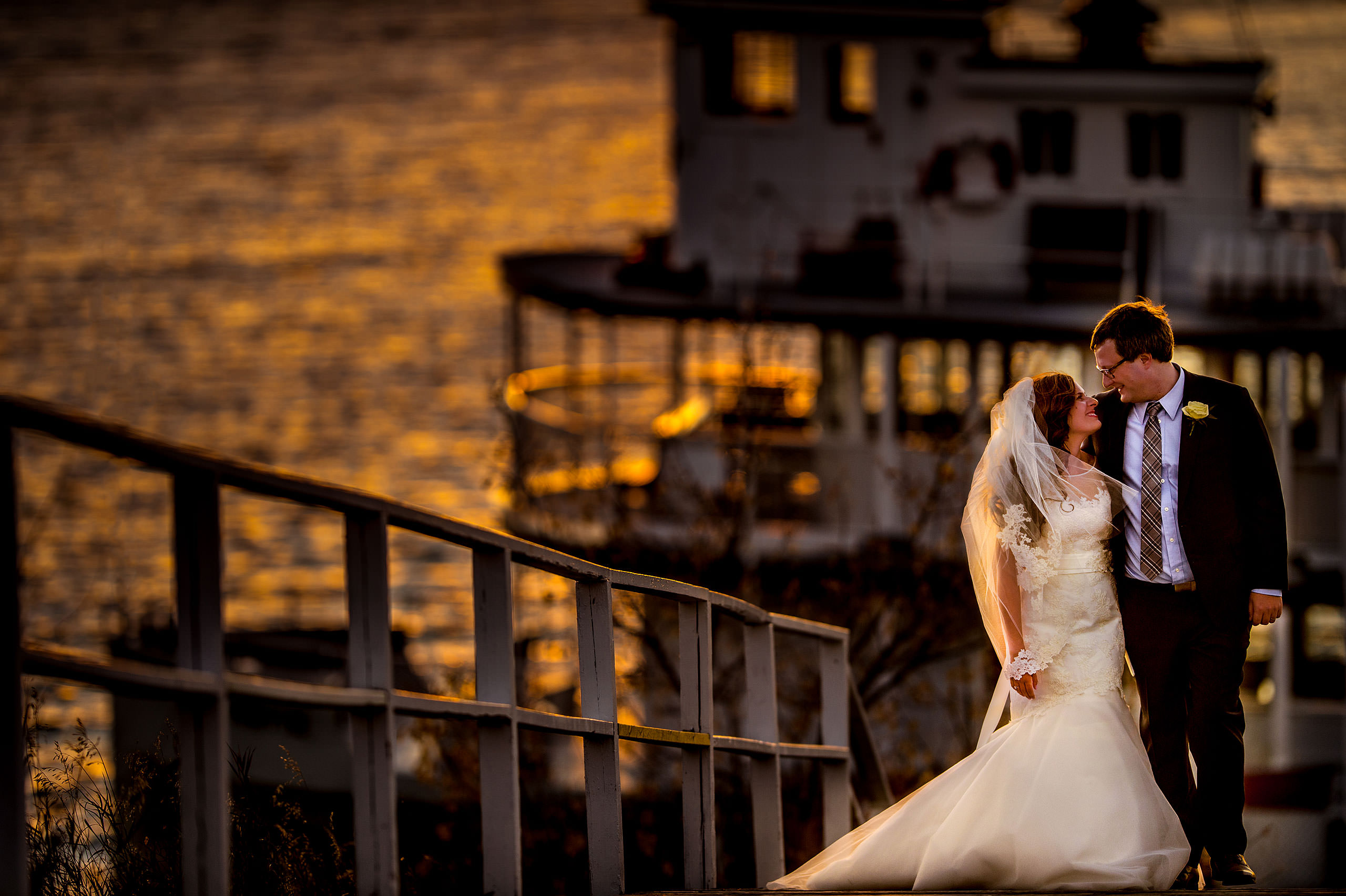 bride and groom walking together up a boat dock with a boat in the background at dusk by Calgary Jewish Wedding Photographer Sean LeBlanc