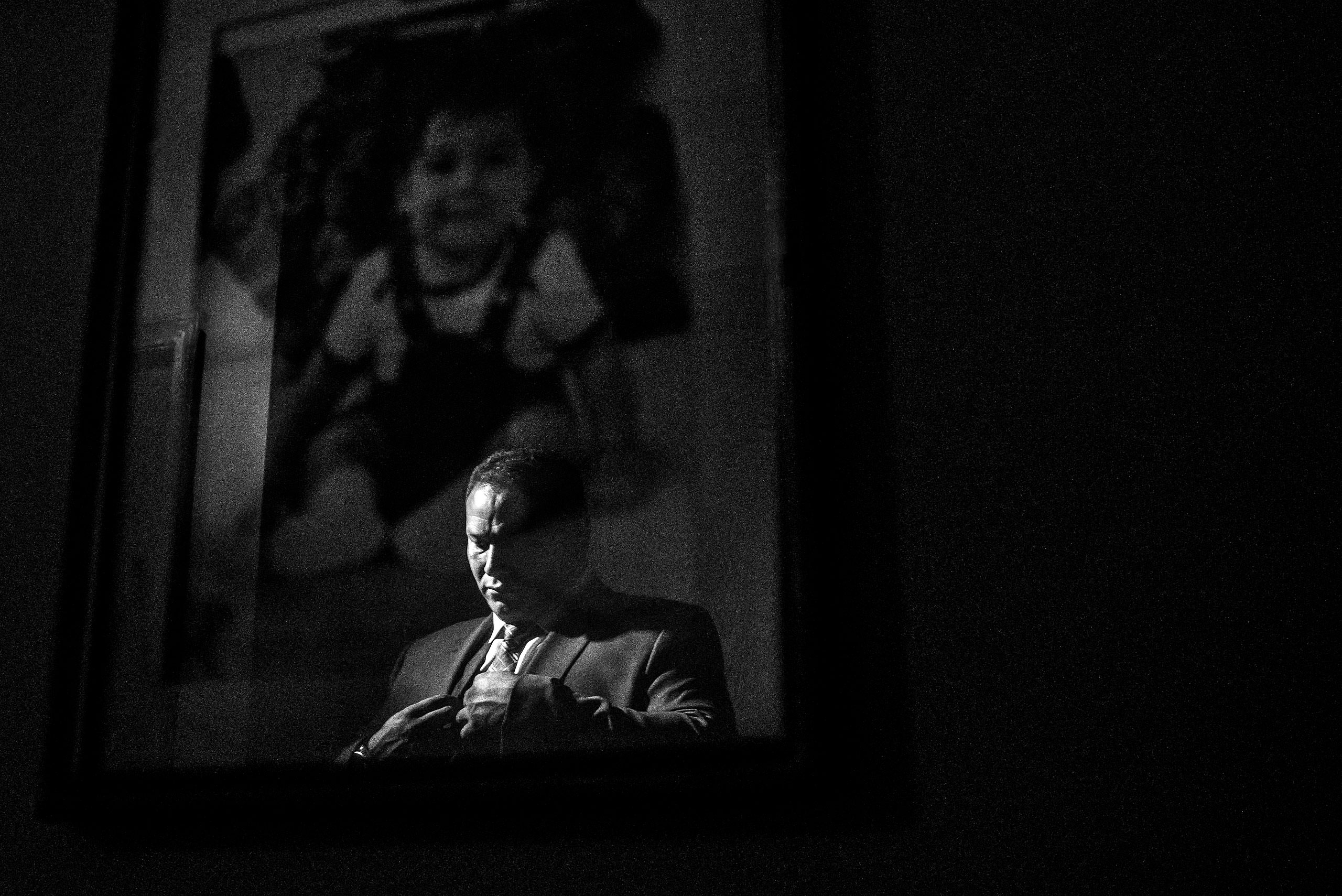 a reflection of a groom in a photo hanging on a wall by Edmonton wedding photographer sean leblanc