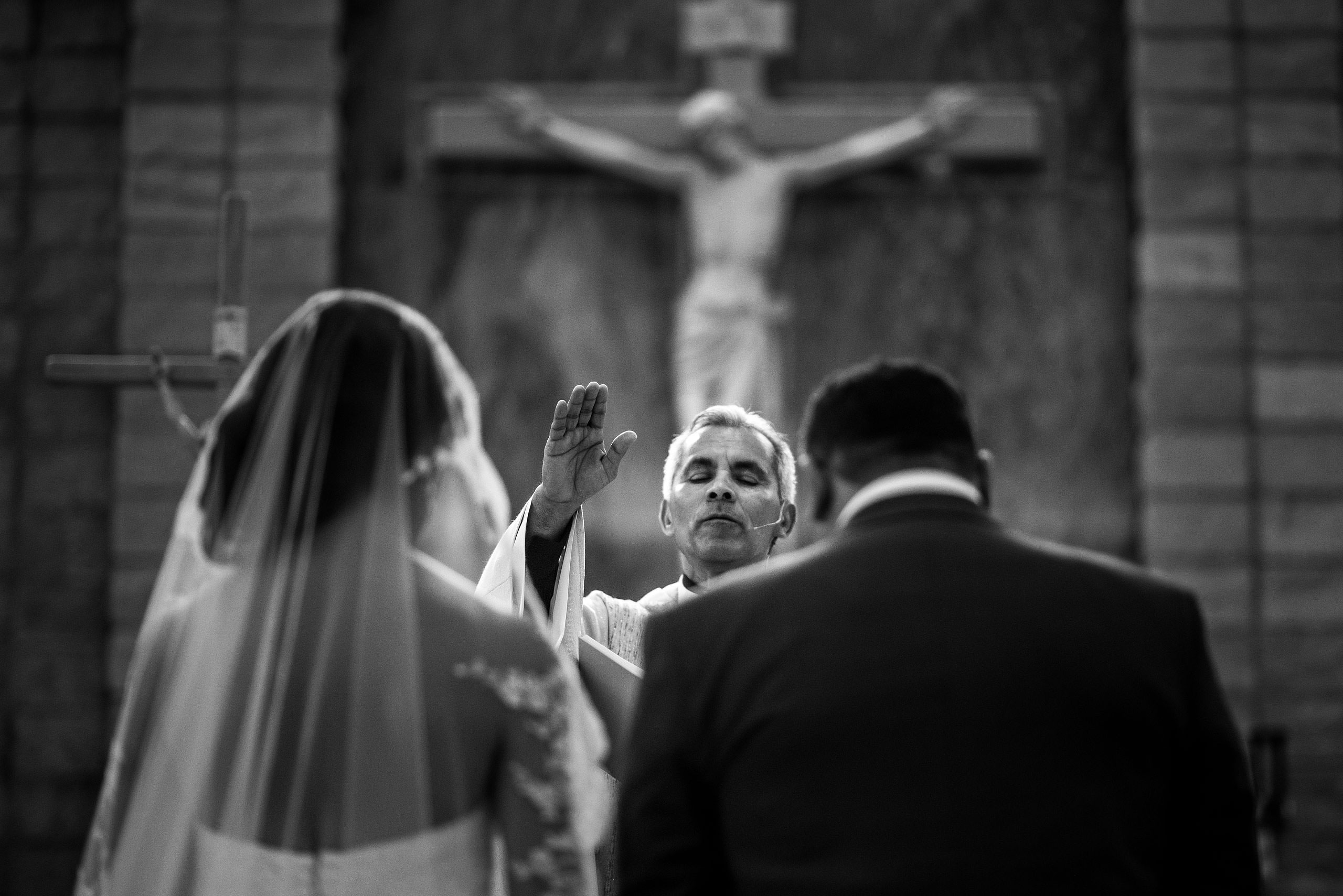 a priest praying for a bride and groom by Edmonton wedding photographer sean leblanc