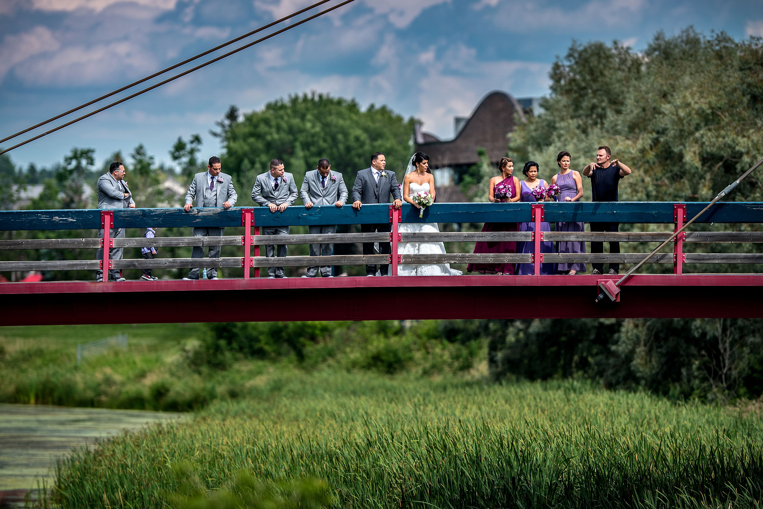 a man speaking to a bridal party on a bridge by Edmonton wedding photographer sean leblanc