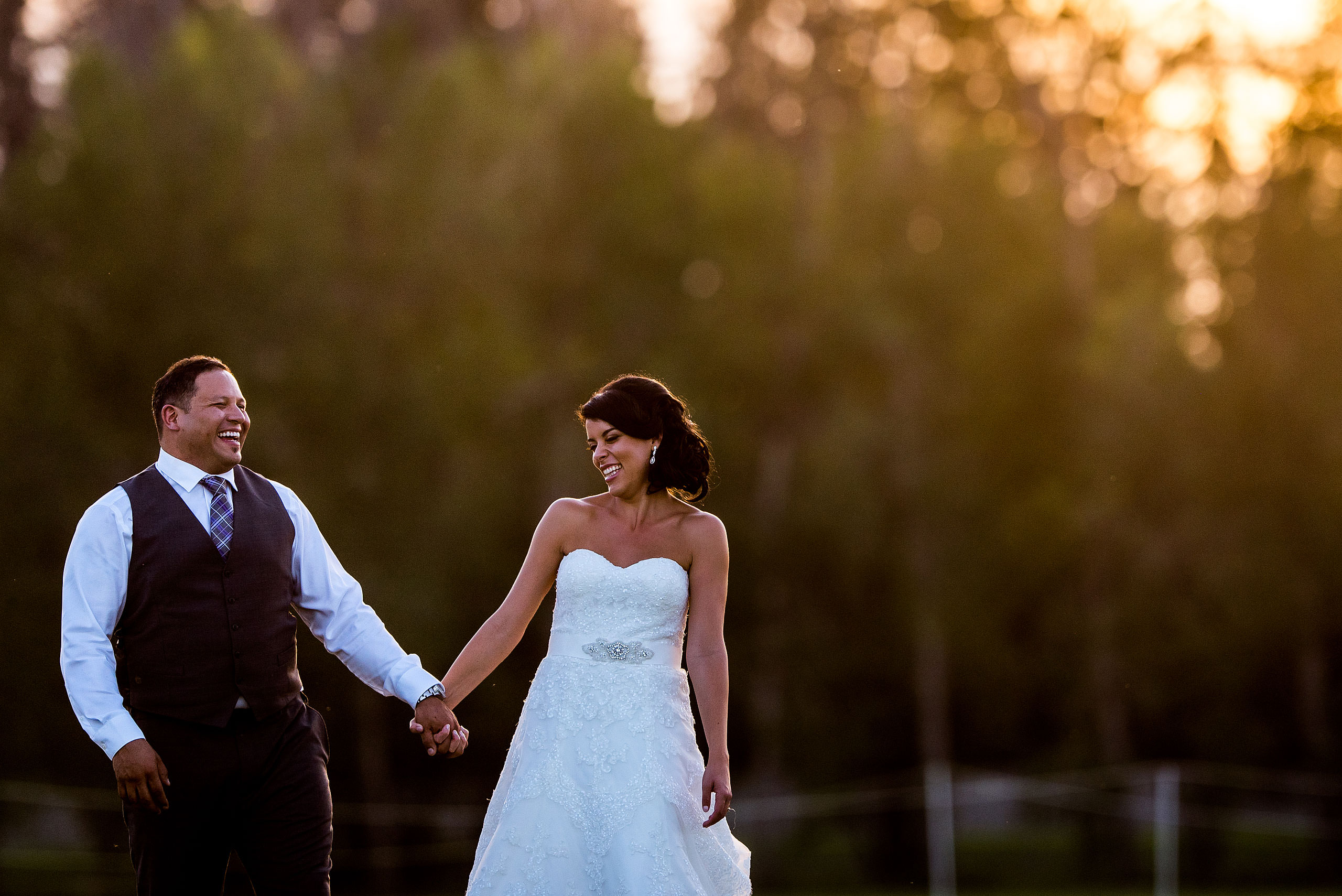 a bride and groom smiling at each other while walking in a field by Edmonton wedding photographer sean leblanc