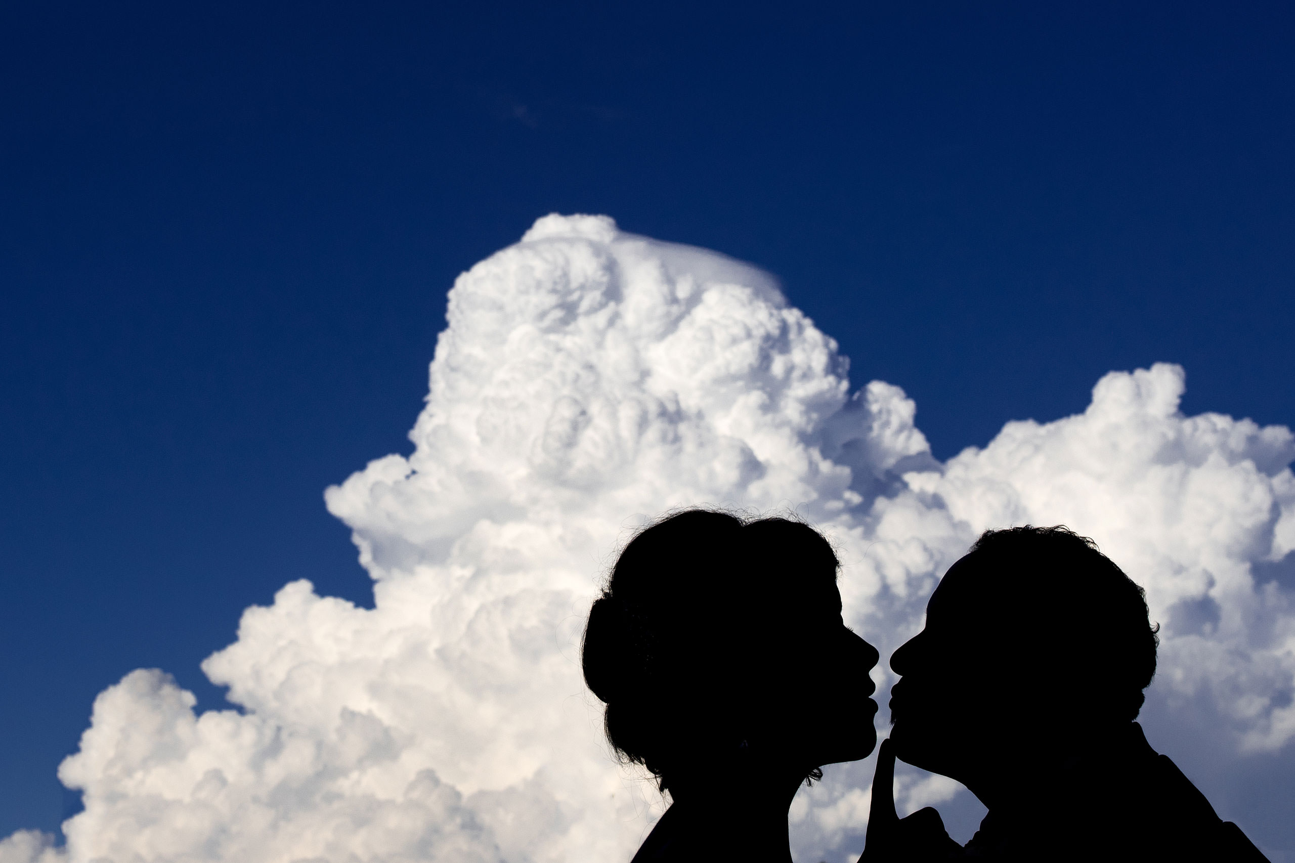 a silhouette of a bride and groom in front of a cloud by Edmonton wedding photographer sean leblanc