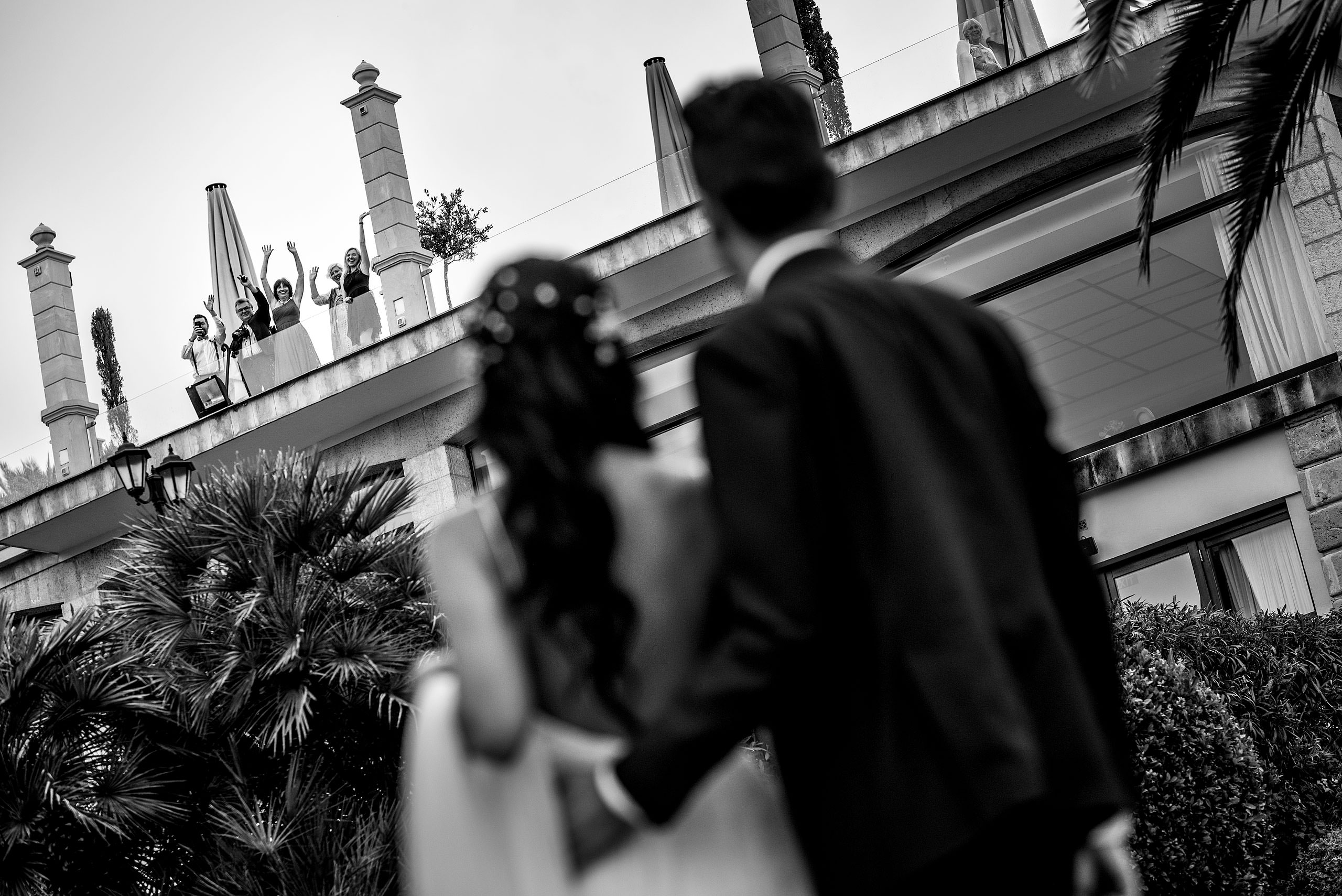 a bride and groom waving a friends on top of a roof at castillo hotel son vida destination wedding by sean leblanc