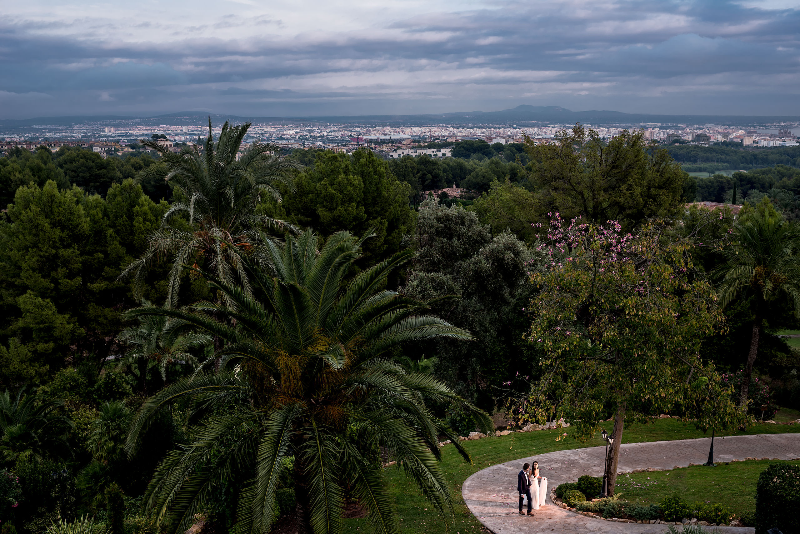 a bride and groom walking up a pathway with a town in the background at castillo hotel son vida destination wedding by sean leblanc