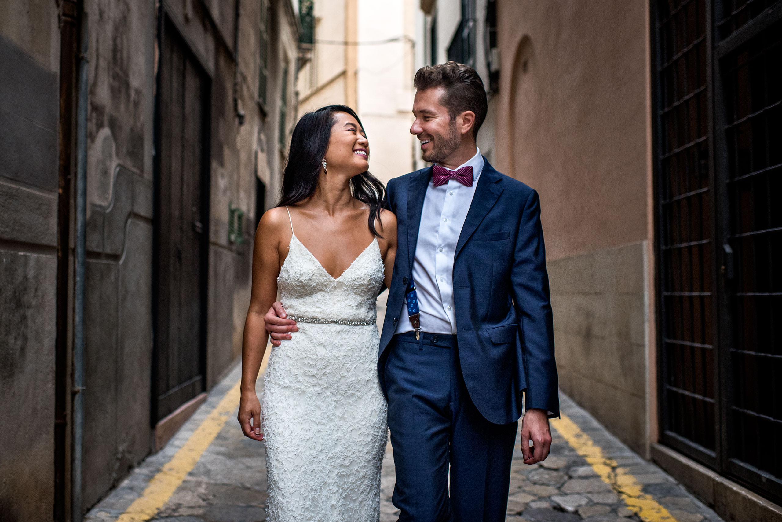 a bride and groom walking down an alleyway with their arms around each other at castillo hotel son vida destination wedding by sean leblanc