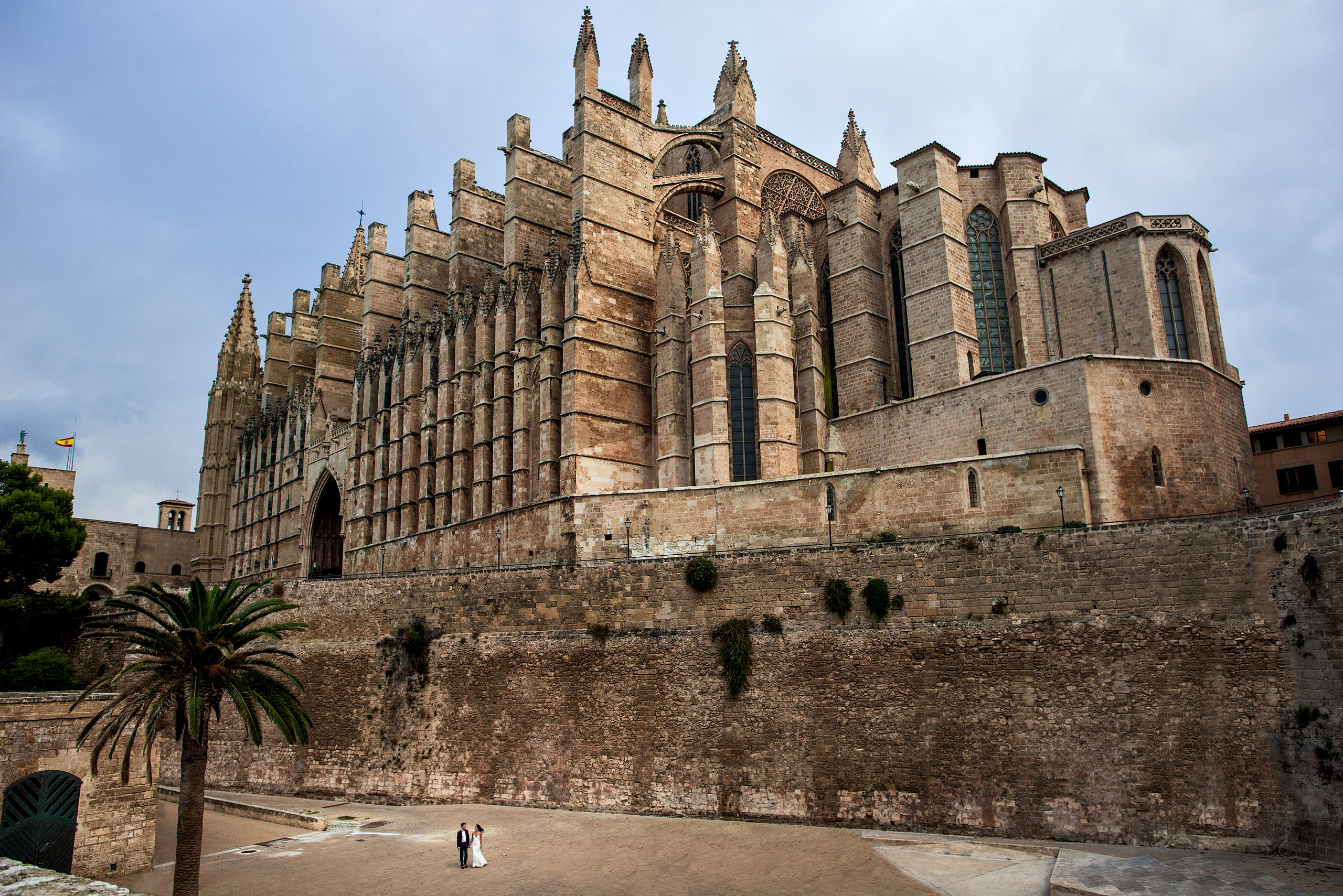 a bride and groom walking in front of the Palma cathedral at castillo hotel son vida destination wedding by sean leblanc