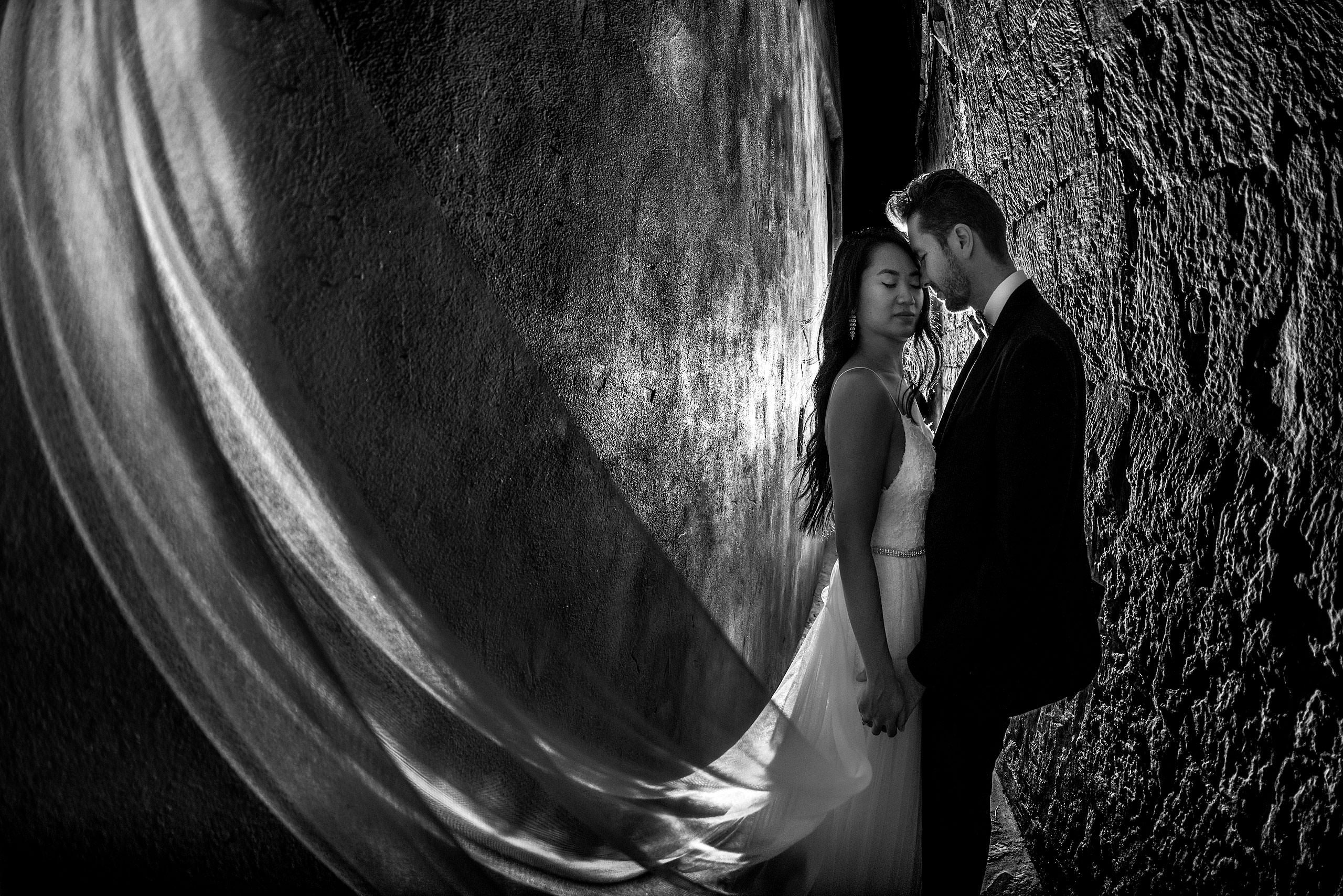 a bride and groom embracing with the brides veil in the wind at castillo hotel son vida destination wedding by sean leblanc