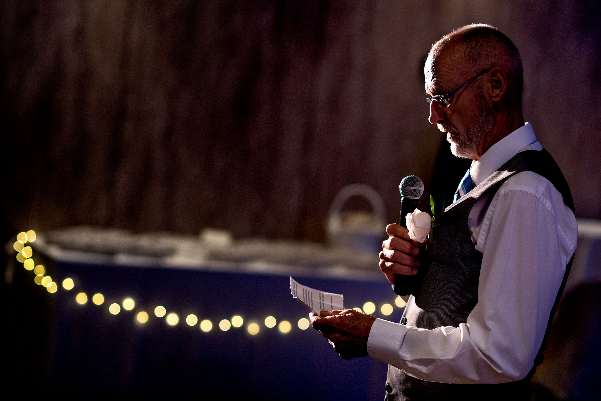 an elderly man reading from a paper and holding a mic at castillo hotel son vida destination wedding by sean leblanc