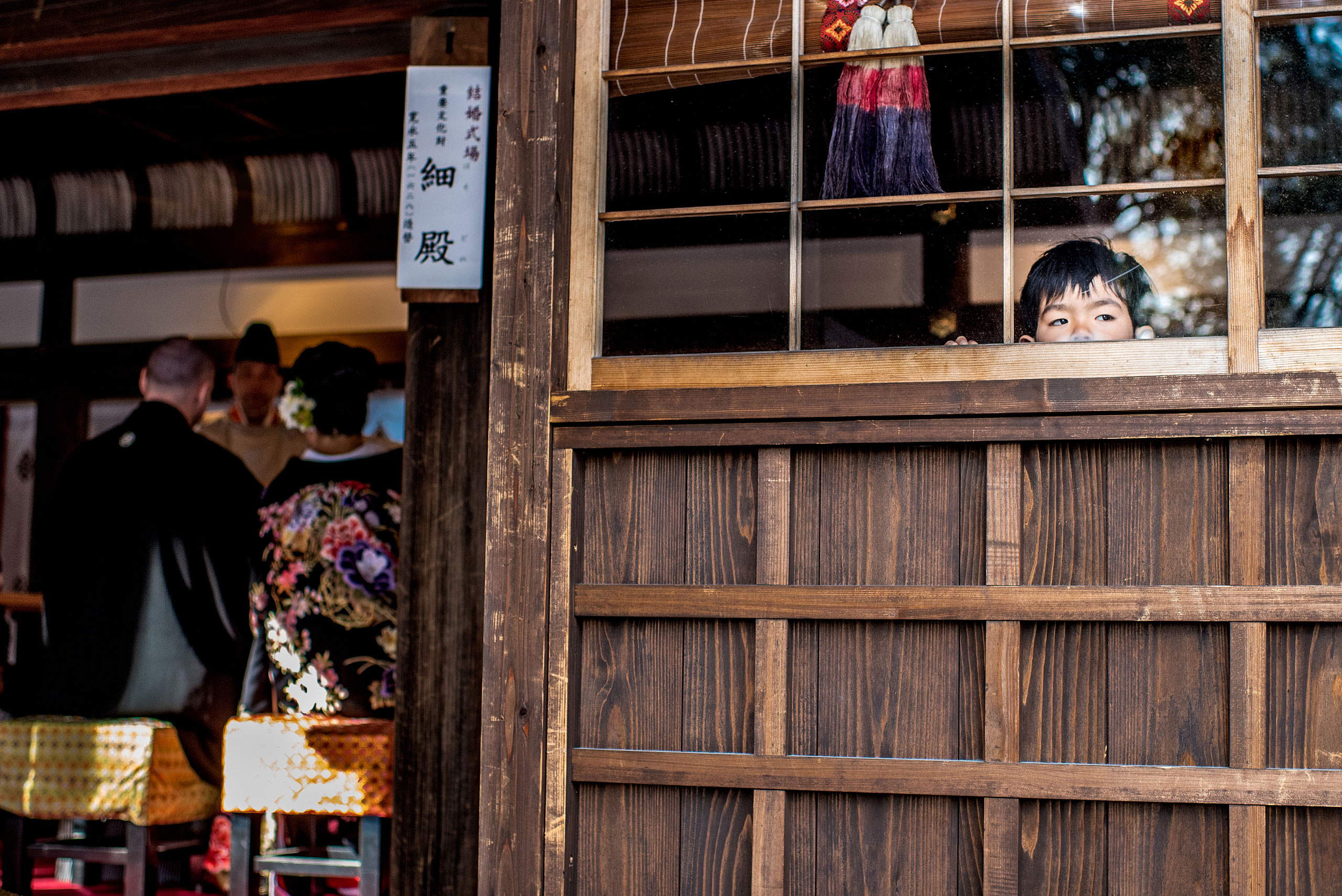 a boy looking out a widow at a ceremony by Japan Destination Wedding Photographer Sean LeBlanc