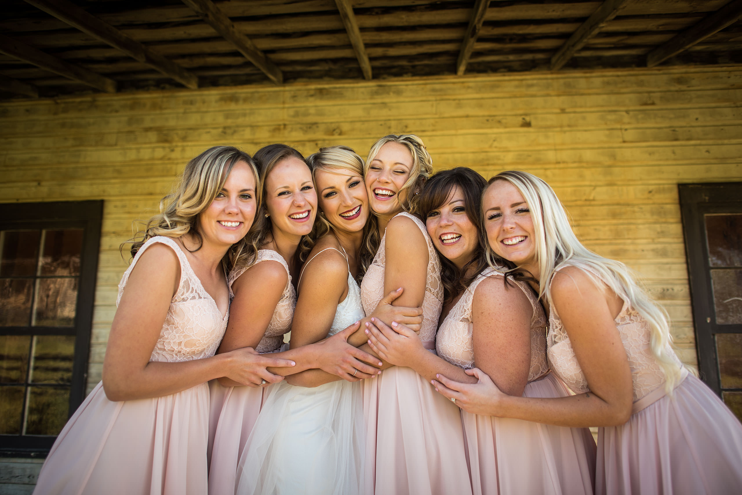 bridesmaids hugging in front of a house at Cochrane Country Wedding by Sean LeBlanc