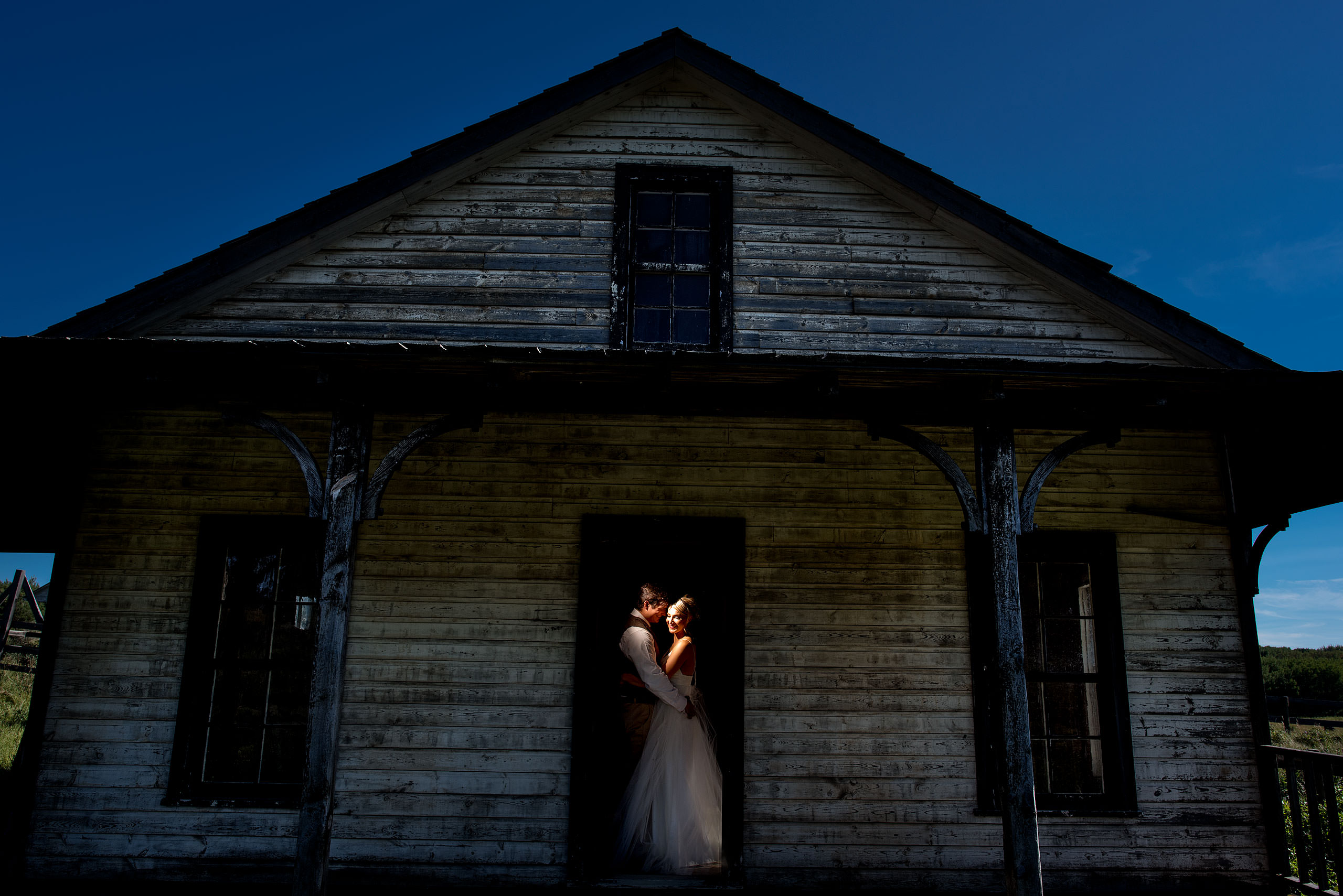 a bride and groom standing in the doorway of an old house at Cochrane Country Wedding by Sean LeBlanc